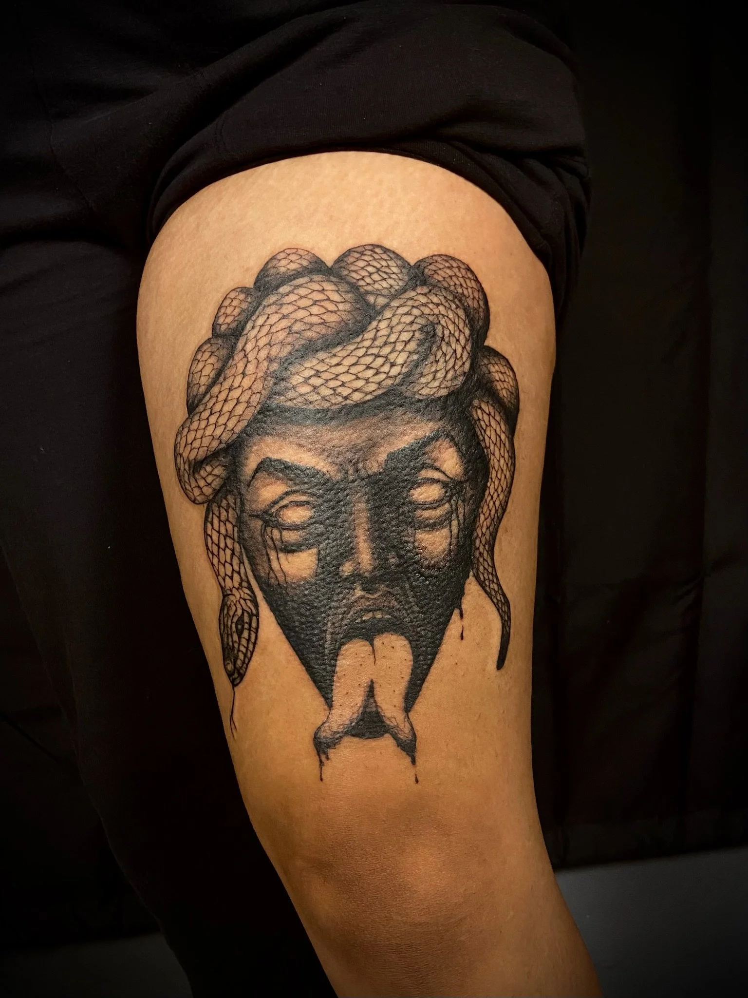 Tattoo of a woman's face with a snake coiled around her head.