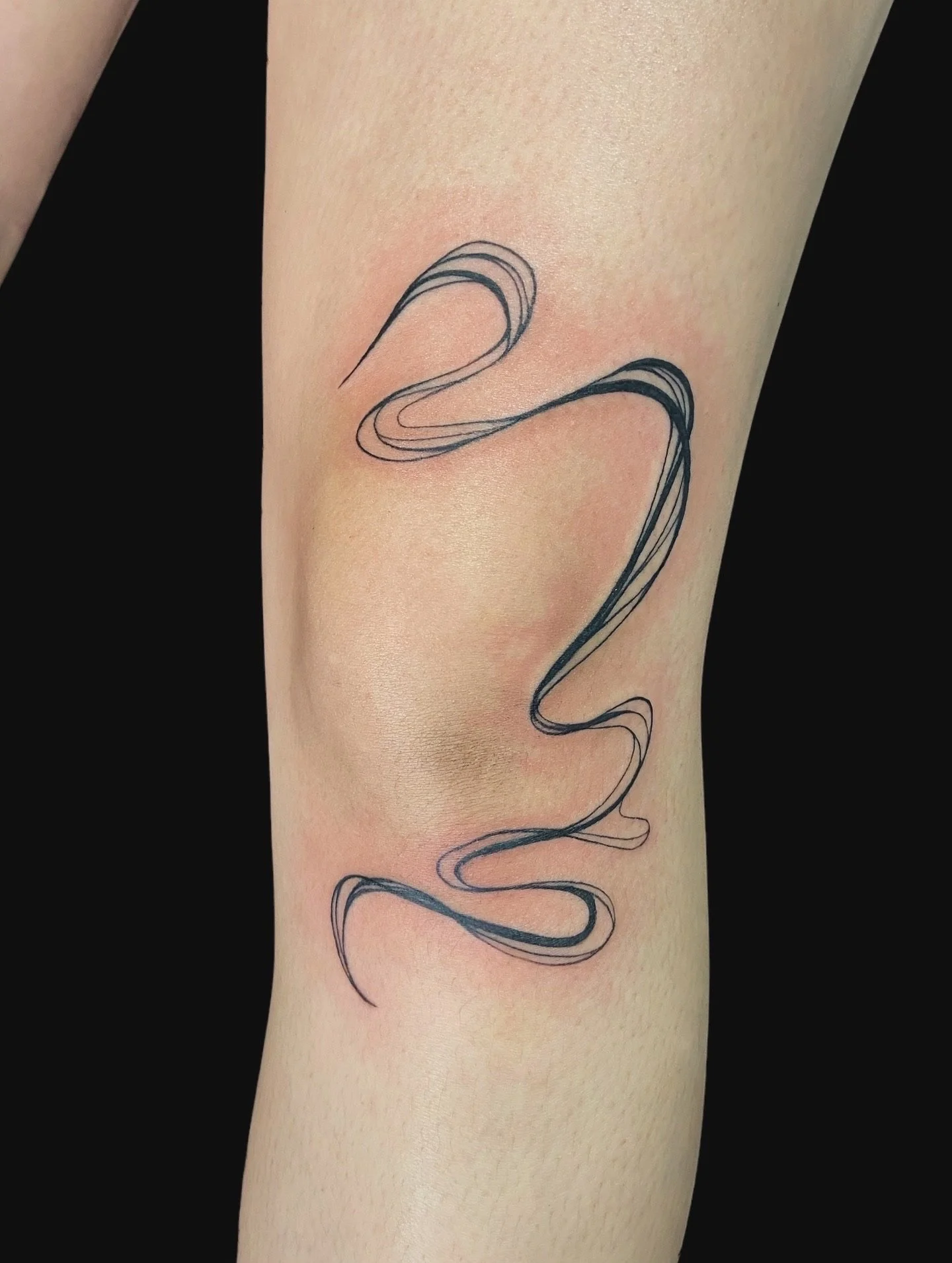 Tattoo of a black abstract line design on a person's arm.