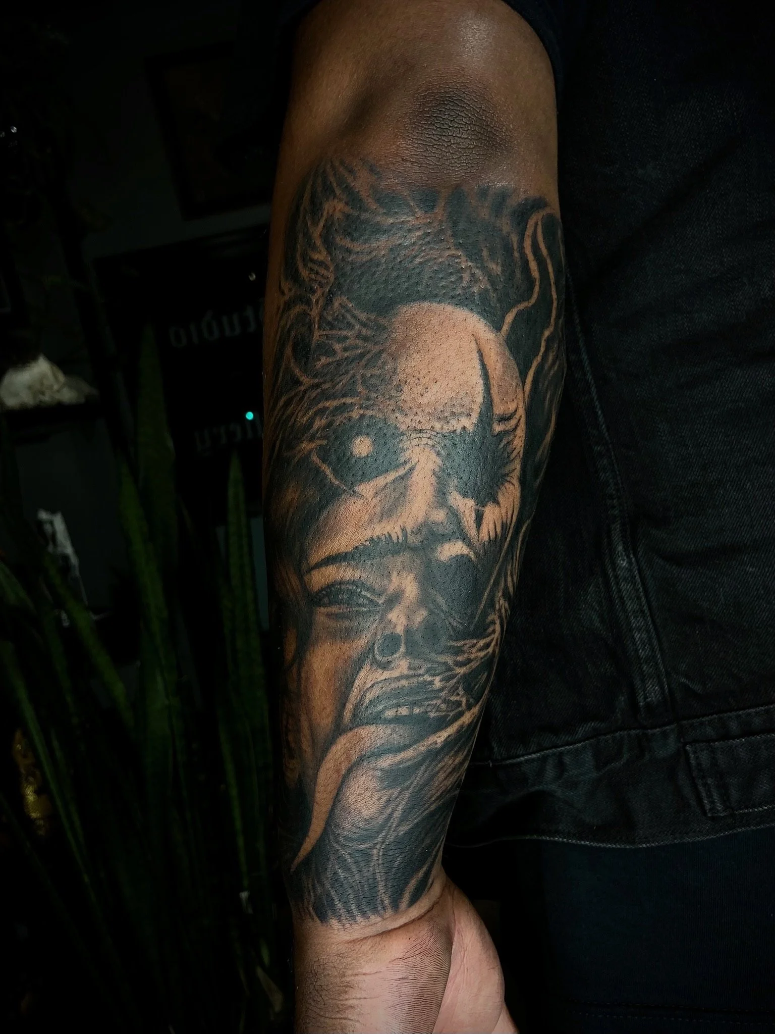 A person's arm with a detailed black and gray tattoo of a skull and a lion's head.