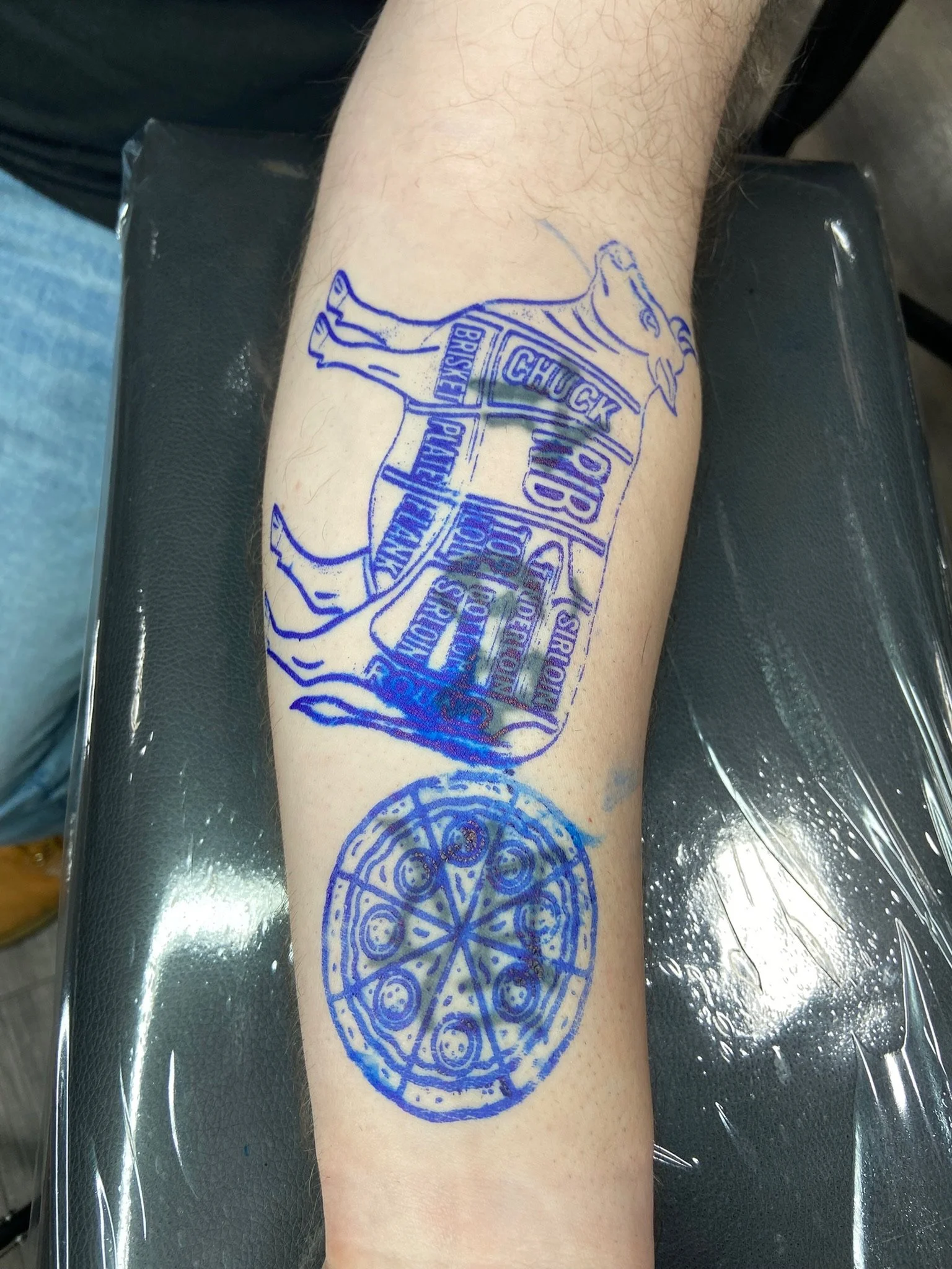 Tattoo of the Chicago Cubs logo on a person's forearm, featuring a blue bear cub holding a baseball bat