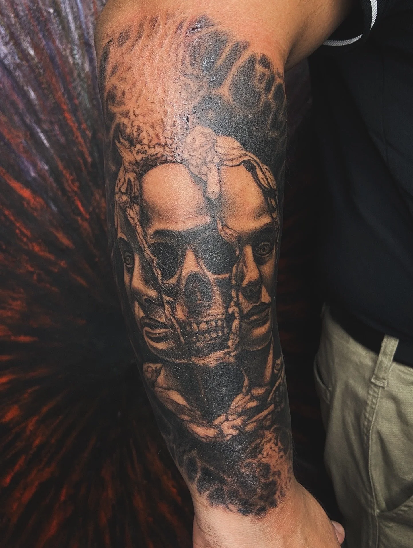Tattoo of a realistic human skull on a person's forearm with other artistic elements surrounding it.