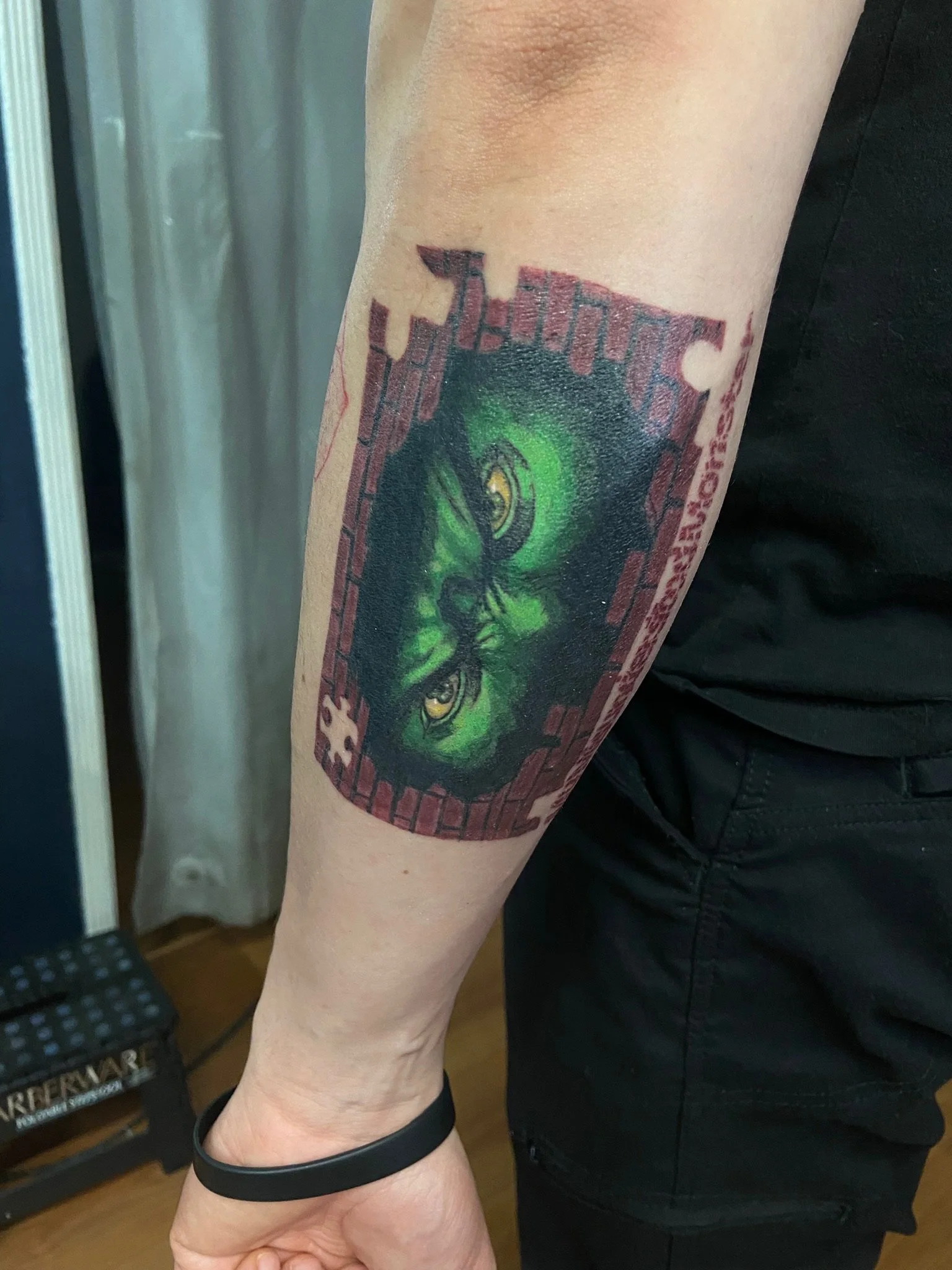 Tattoo of a green wolf face on the person's upper arm.