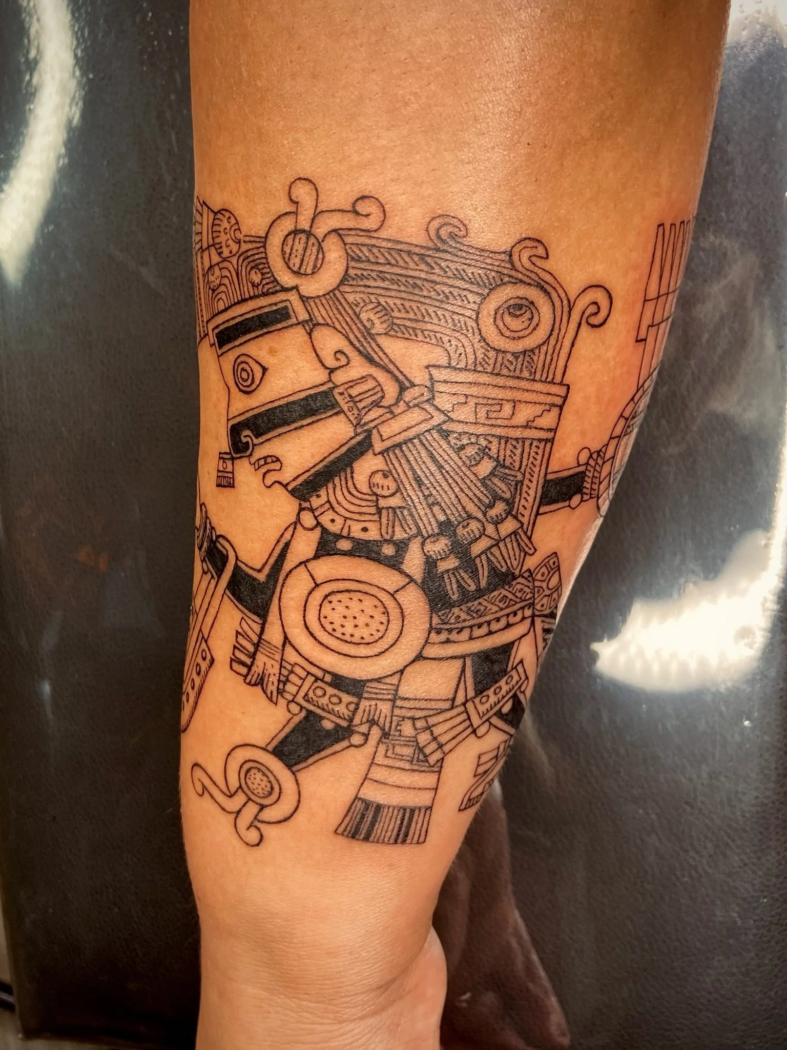 Line art tattoo of a piano keyboard, musical notes, and swirling designs on a person's arm.