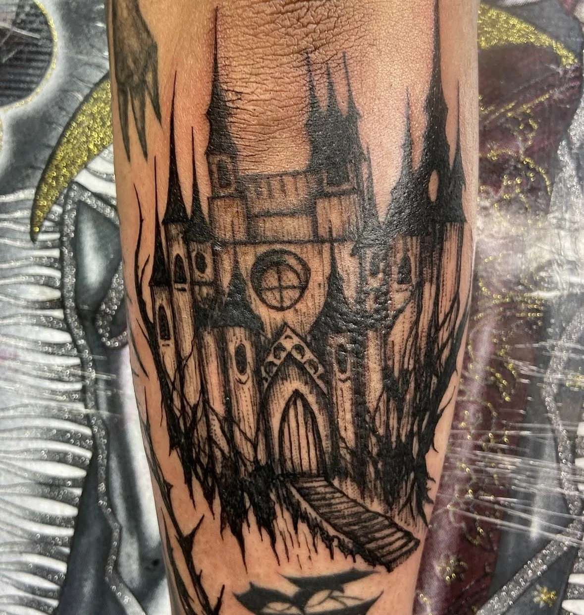 Tattoo of a spooky castle with tall spires, arched windows, and a large door, depicted in black ink on skin by tattoo artist Agua at Floating Streams Tattoo in the Arts District of Downtown Los Angeles.