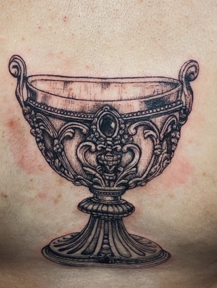 Tattoo of an ornate, vintage-style cup or goblet with intricate detailing and embellishments.