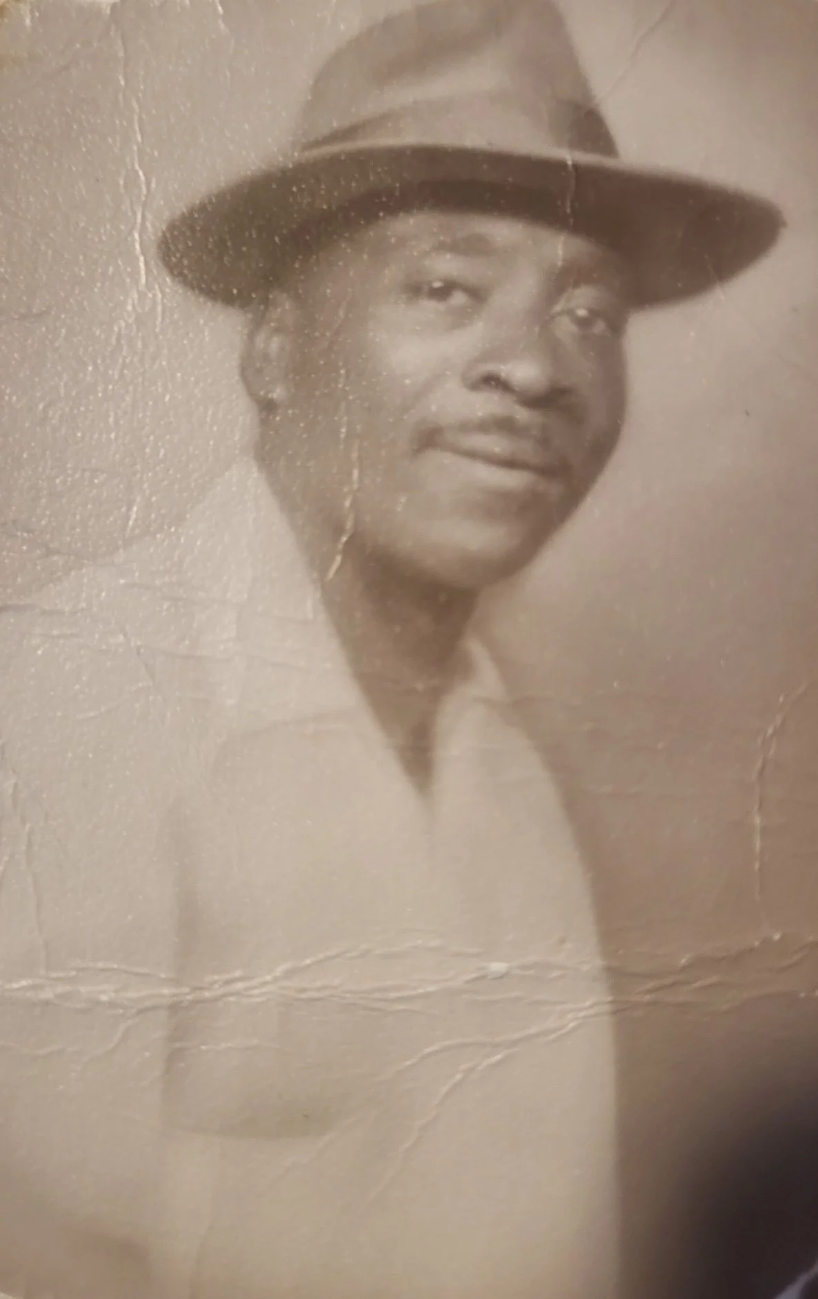 A black-and-white portrait of a woman wearing a wide-brimmed hat, smiling softly.