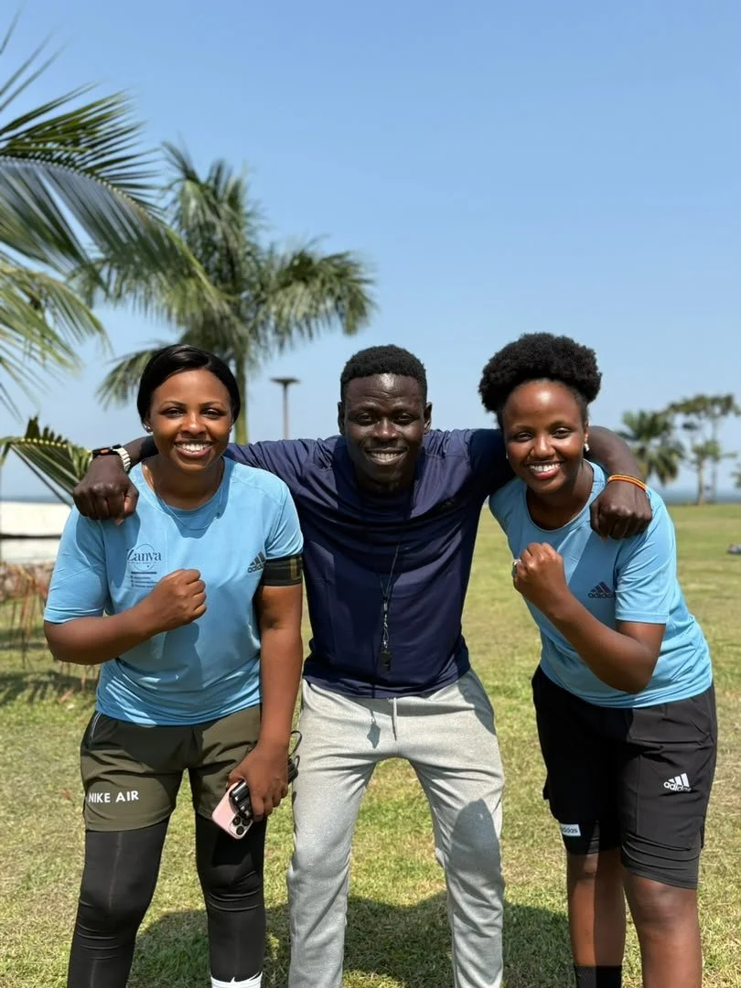 Black-and-white photograph of three smiling Zanya participants with their arms around one another.