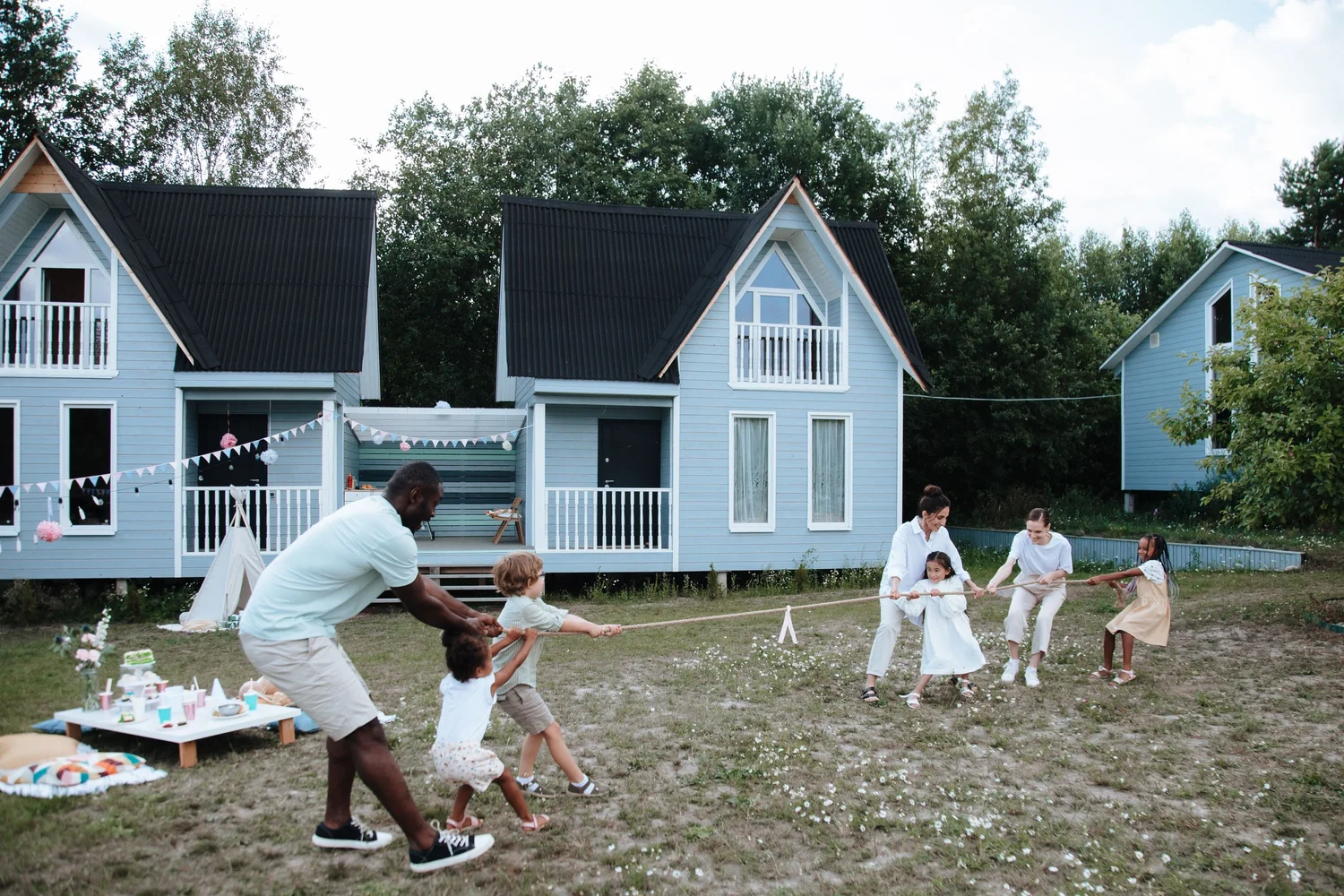 Adults and children playing tug-of-war together outdoors