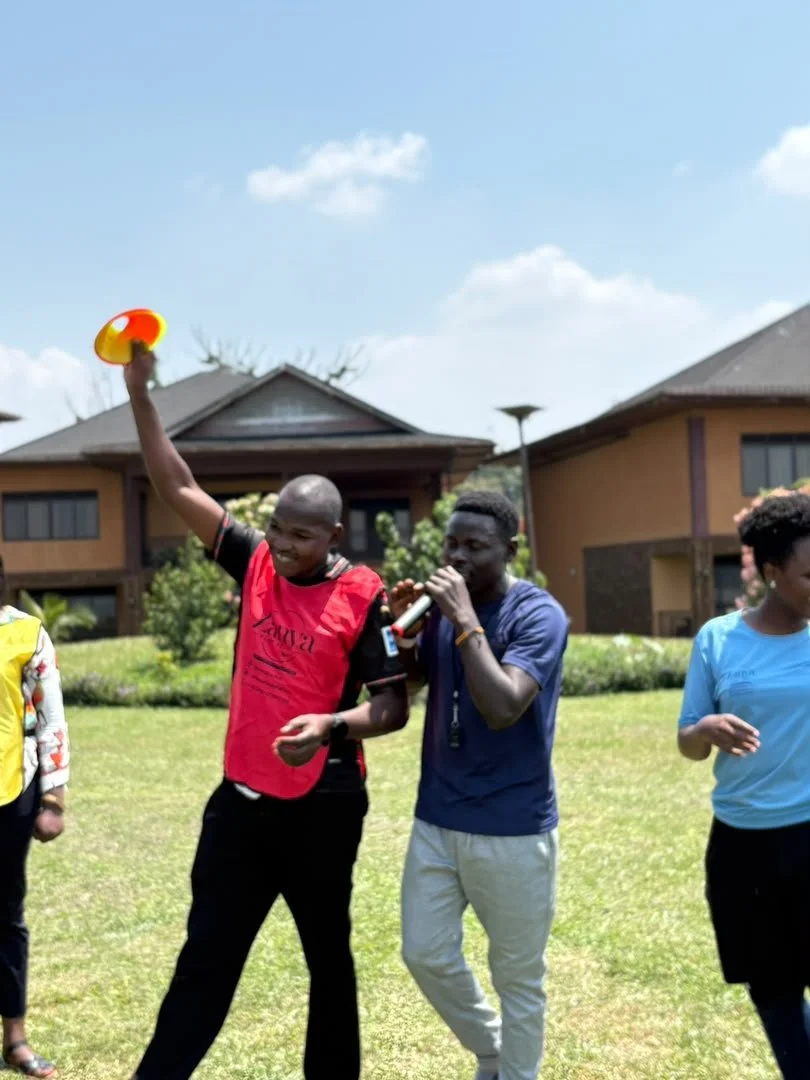 A Zanya host with a microphone beside a smiling participant holding an orange flying disc.