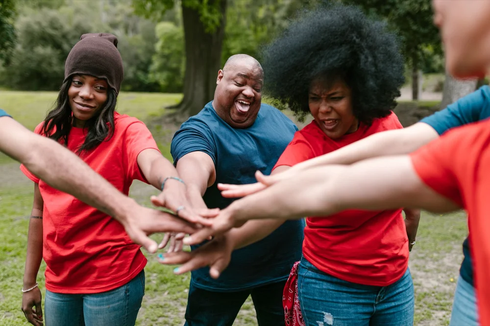 A group joining hands during an outdoor shared challenge