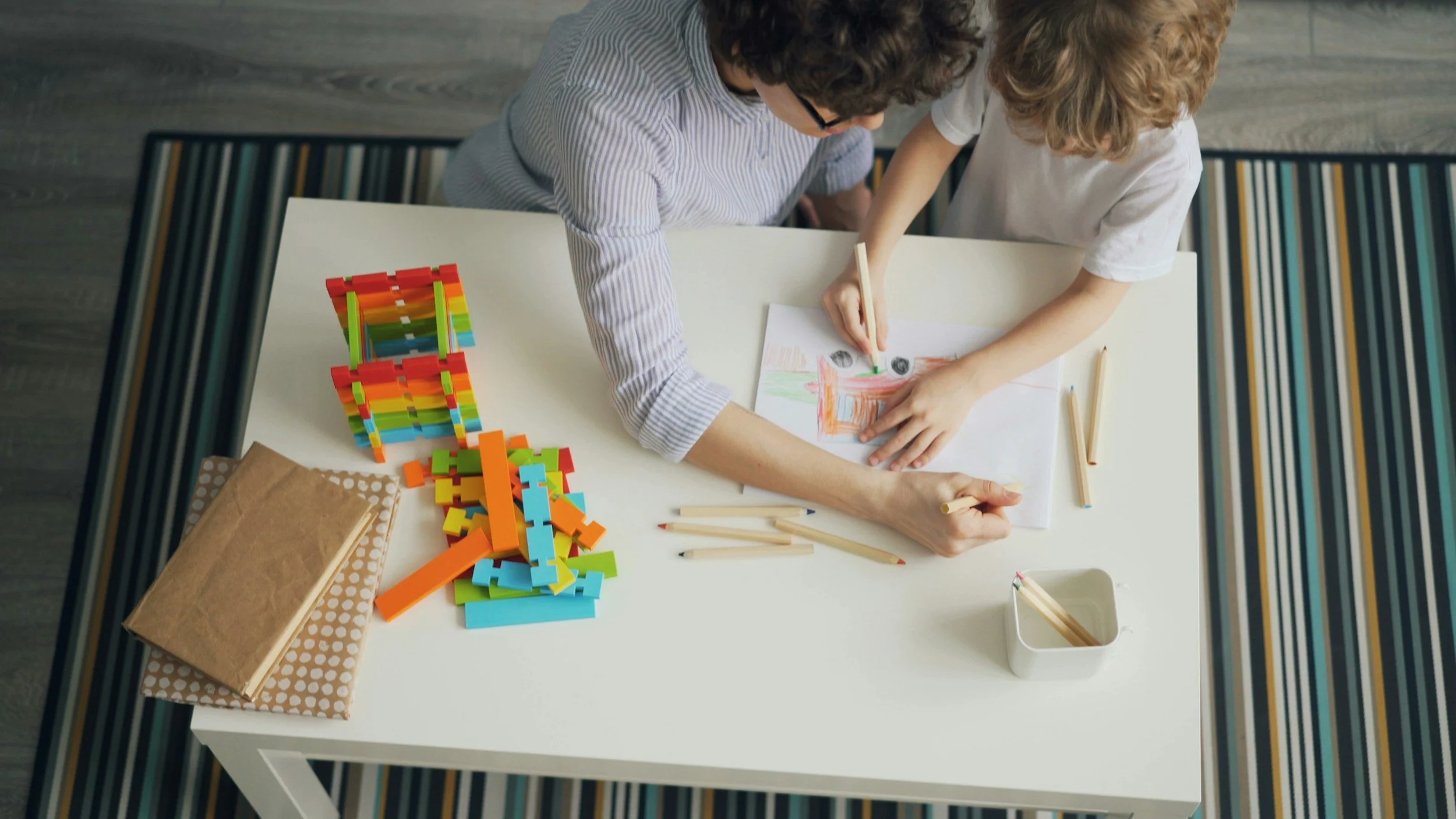 Parent and child working together on a creative activity at a table.