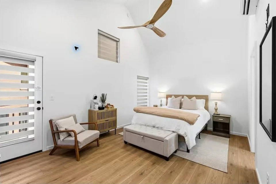 SoKno Haven queen bedroom with high ceiling, modern furnishings, and warm wood accents.
