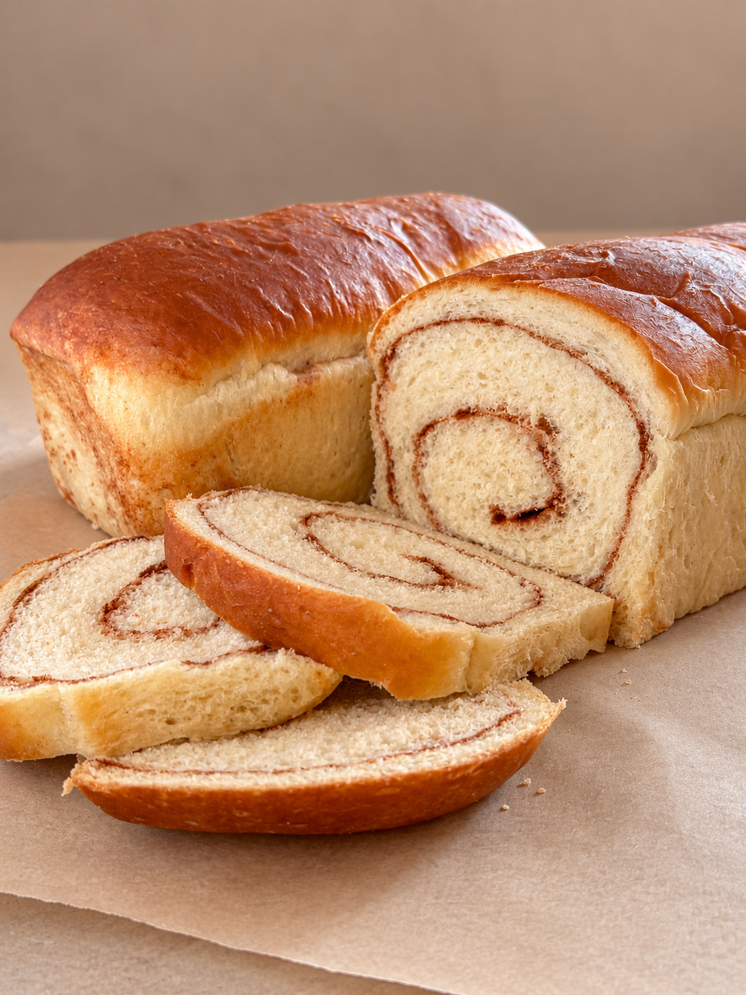 A loaf of swirl bread with slices cut off, displaying a cinnamon swirl inside.
