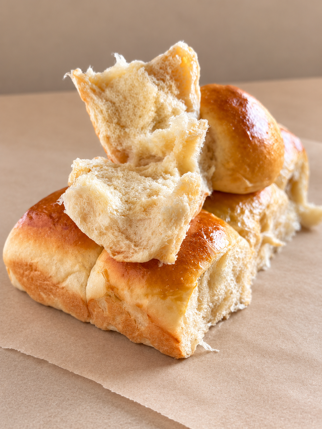 Pieces of bread torn apart and placed on a beige surface.