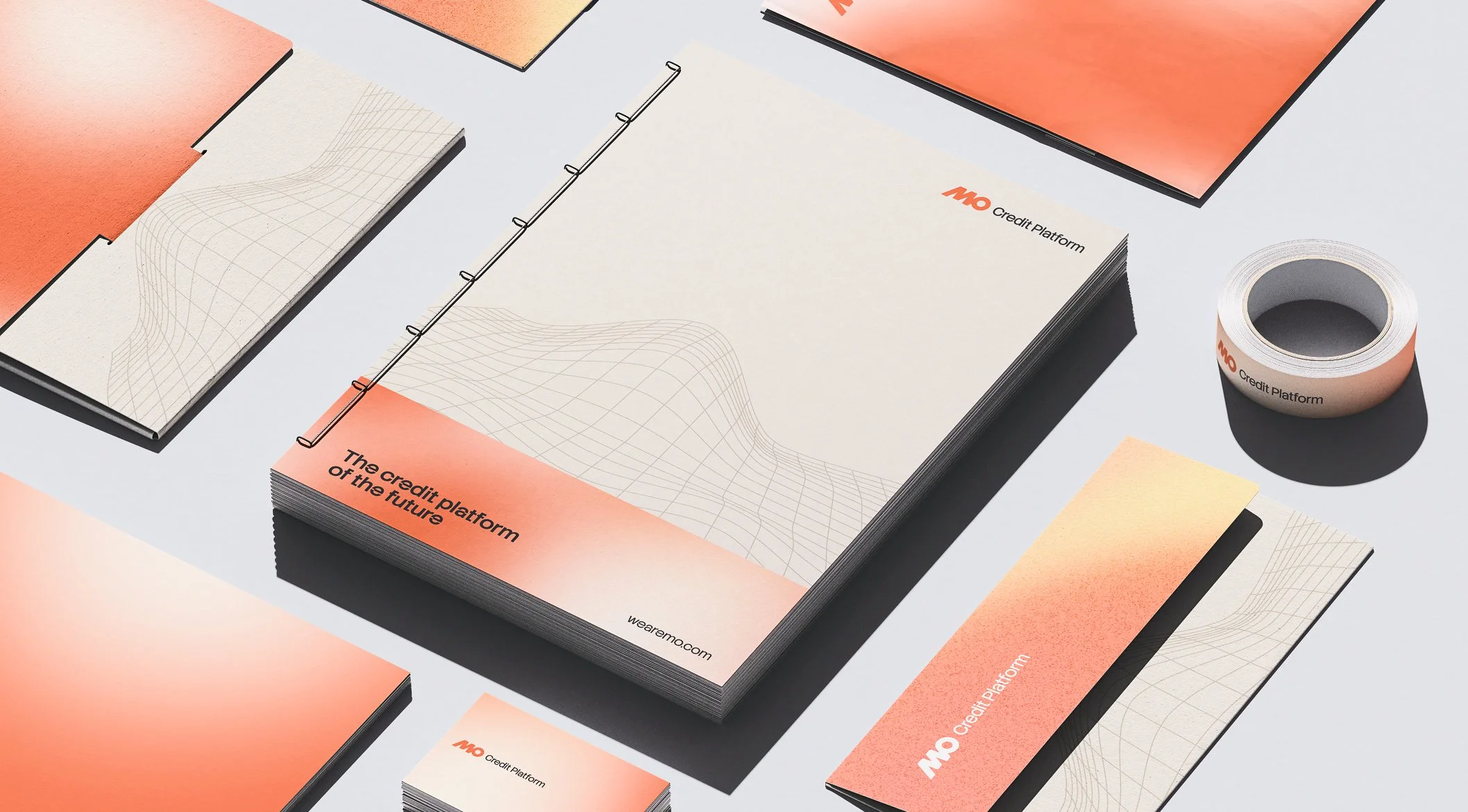 Material promocional de la plataforma de crédito MO, que incluye folletos, una libreta, una cinta adhesiva y tarjetas, con un diseño en tonos anaranjados y beige, y gráficos lineales que representan datos.