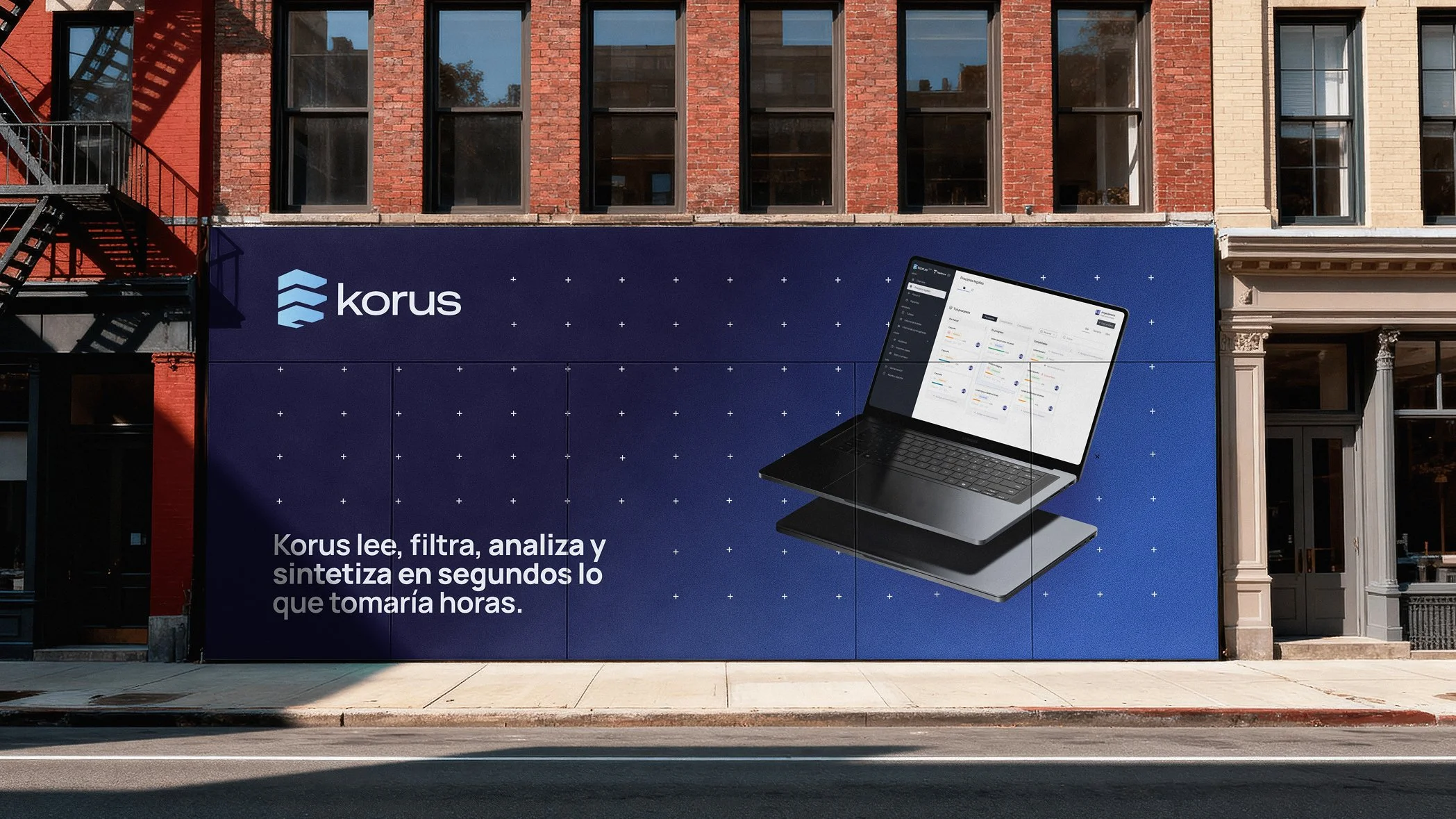Cartel publicitario en una fachada de ladrillo, con logotipo y texto promocional de un software llamado Korus, mostrando una pantalla de computadora portátil con la interfaz del programa.