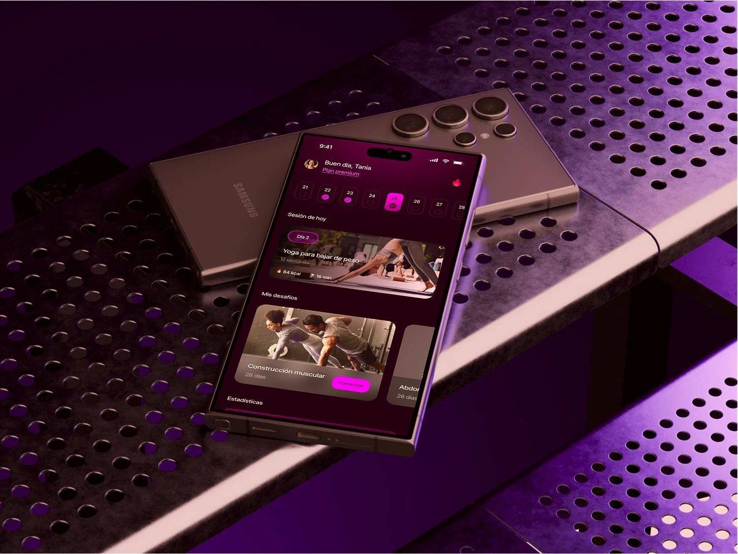 Teléfono móvil negro con pantalla encendida mostrando una aplicación de entrenamiento, colocado sobre una mesa de metal con perforaciones, en un entorno con iluminación morada y negra.