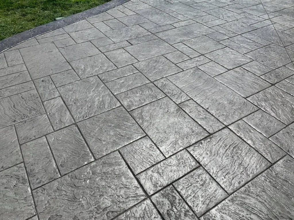 Gray concrete surface with a rectangular stone pattern and textured finish.
