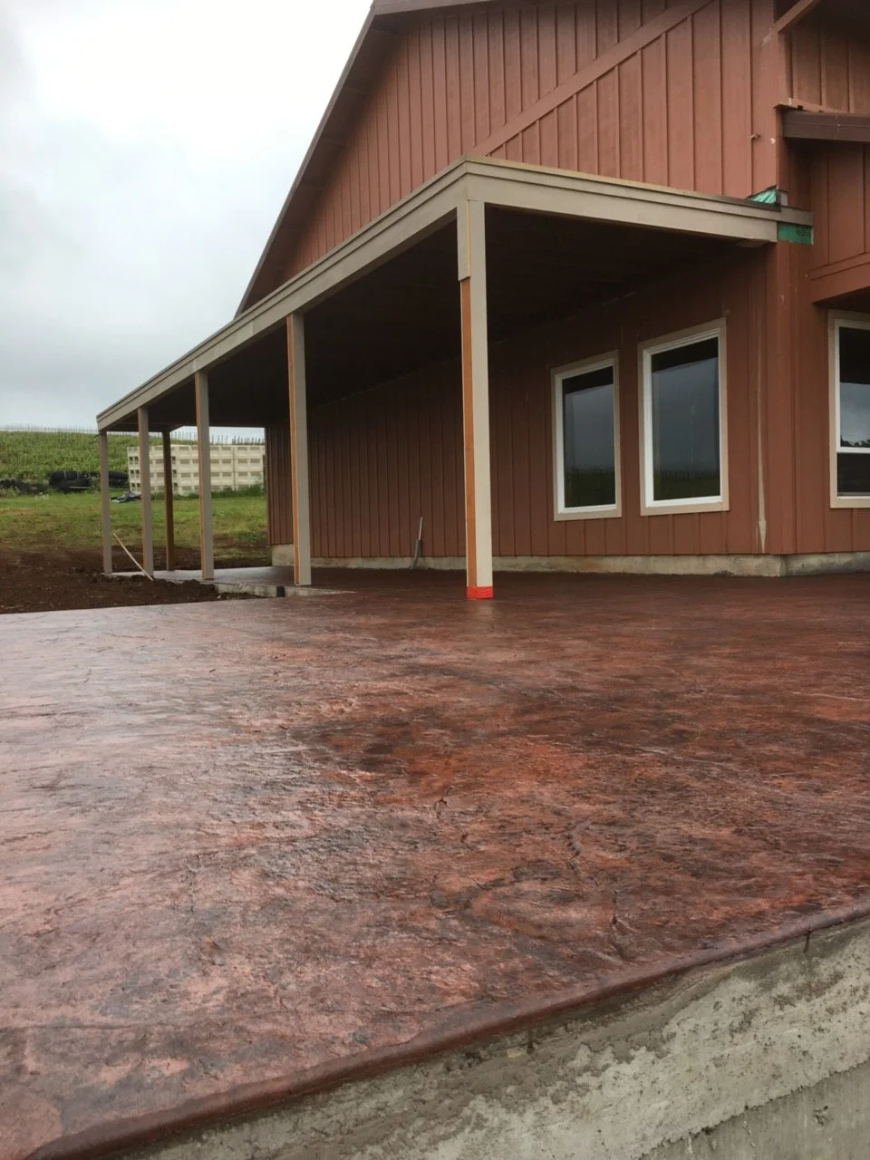 Textured concrete patio beside a covered porch.