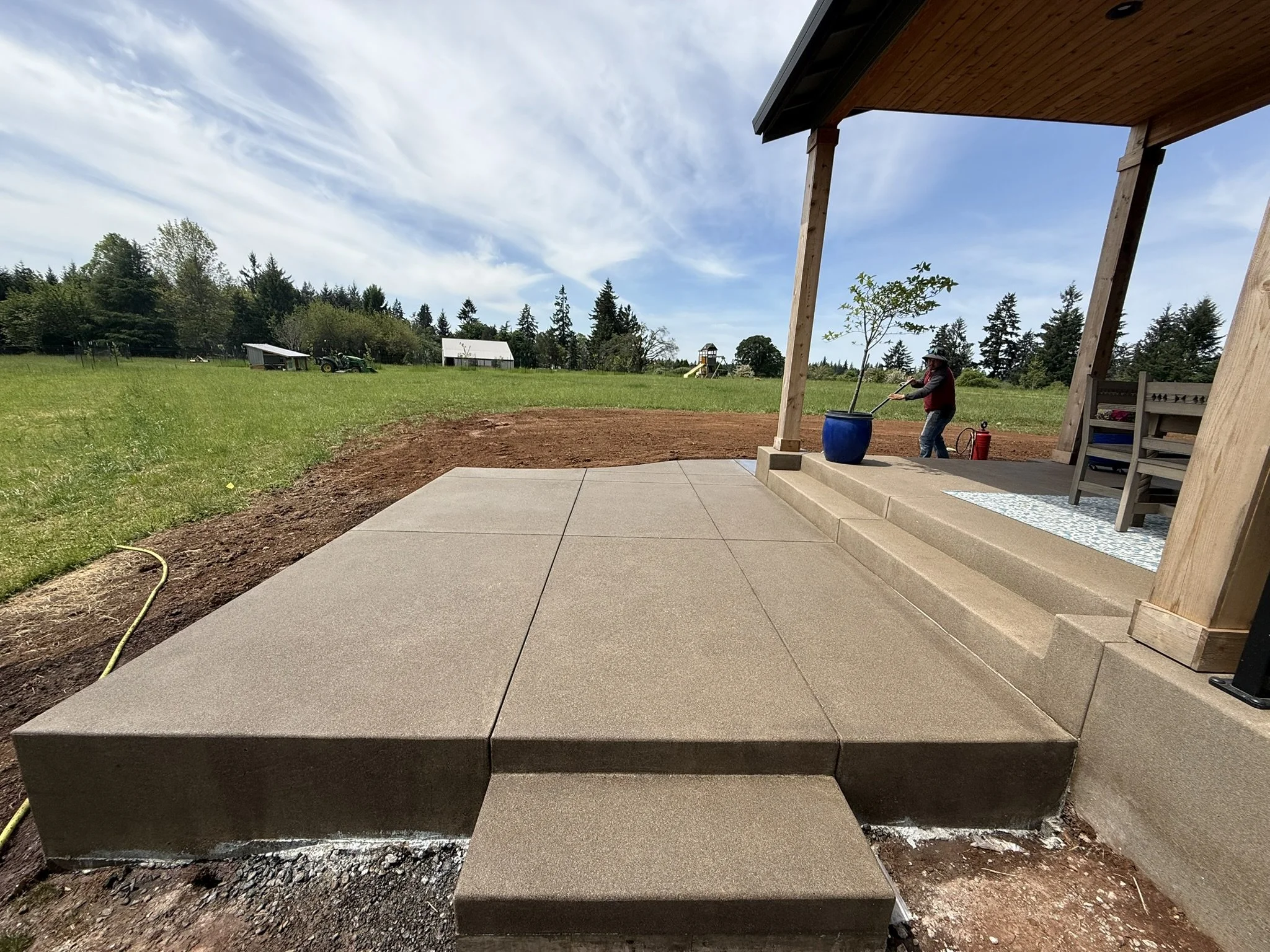 Finished concrete landing and step beside a covered porch.