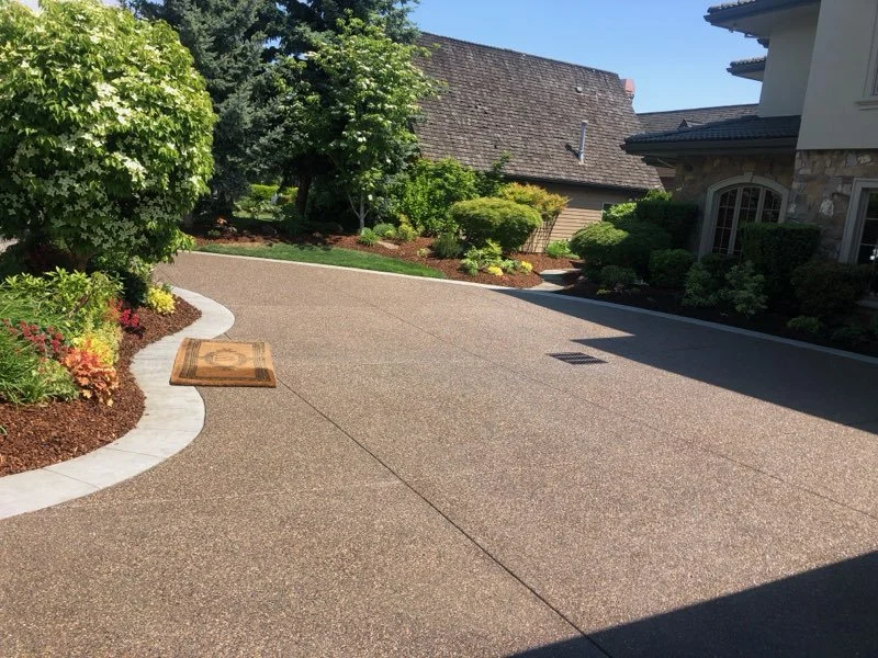 Finished textured concrete driveway with clean control joints and curved borders.