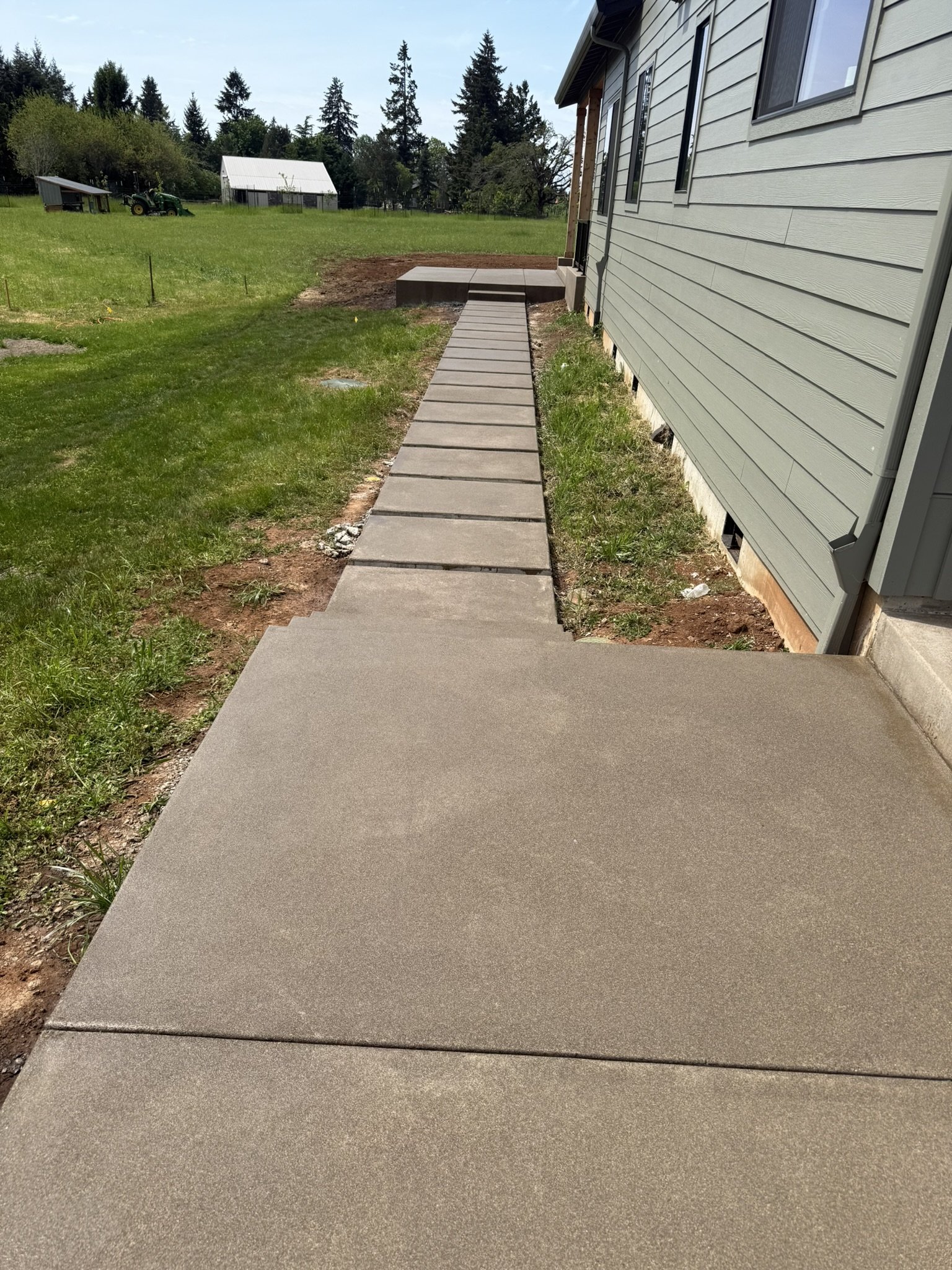 Straight concrete walkway with evenly spaced joints alongside a house.
