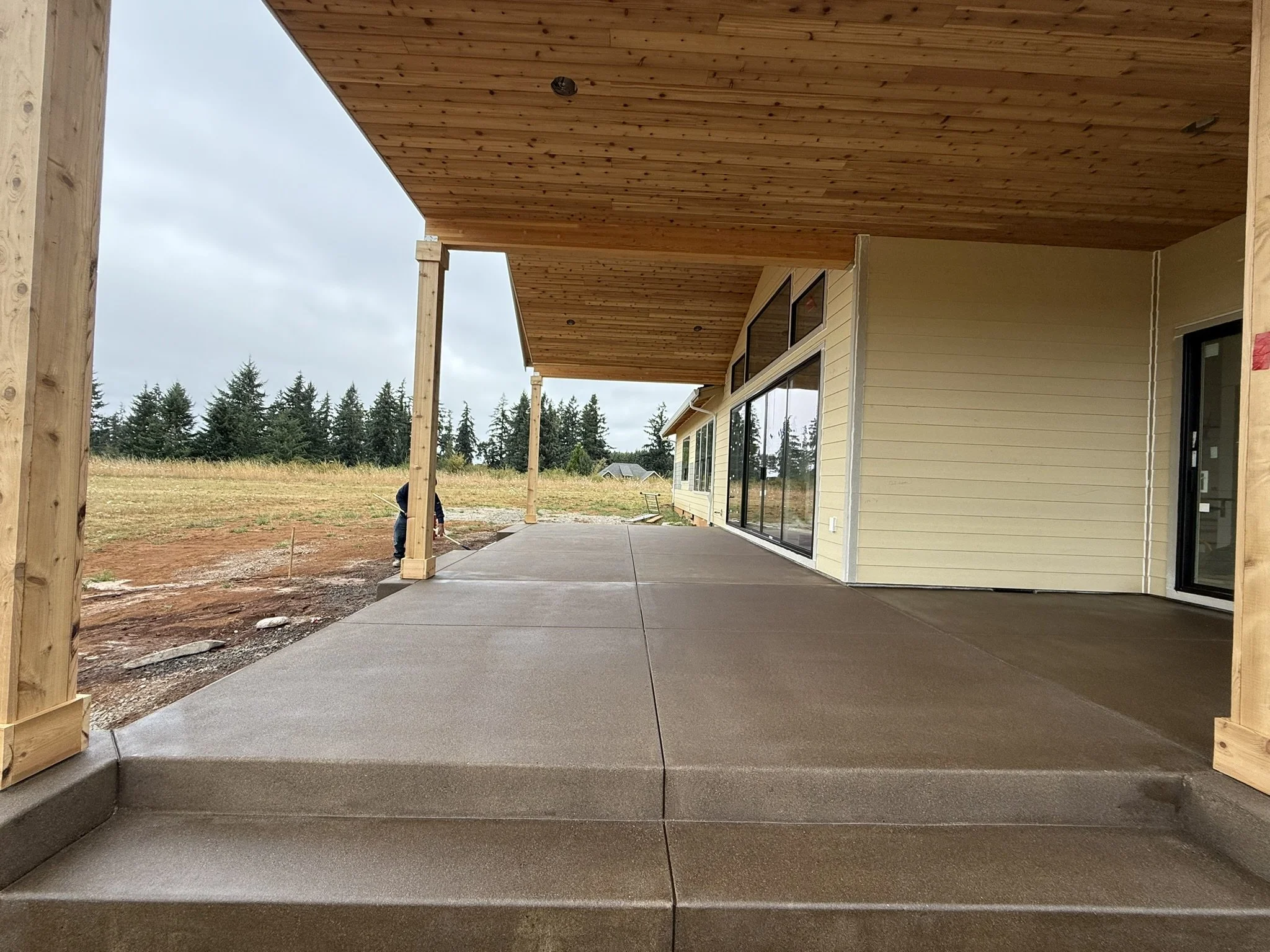 Broad concrete steps leading to a covered patio beside a house.
