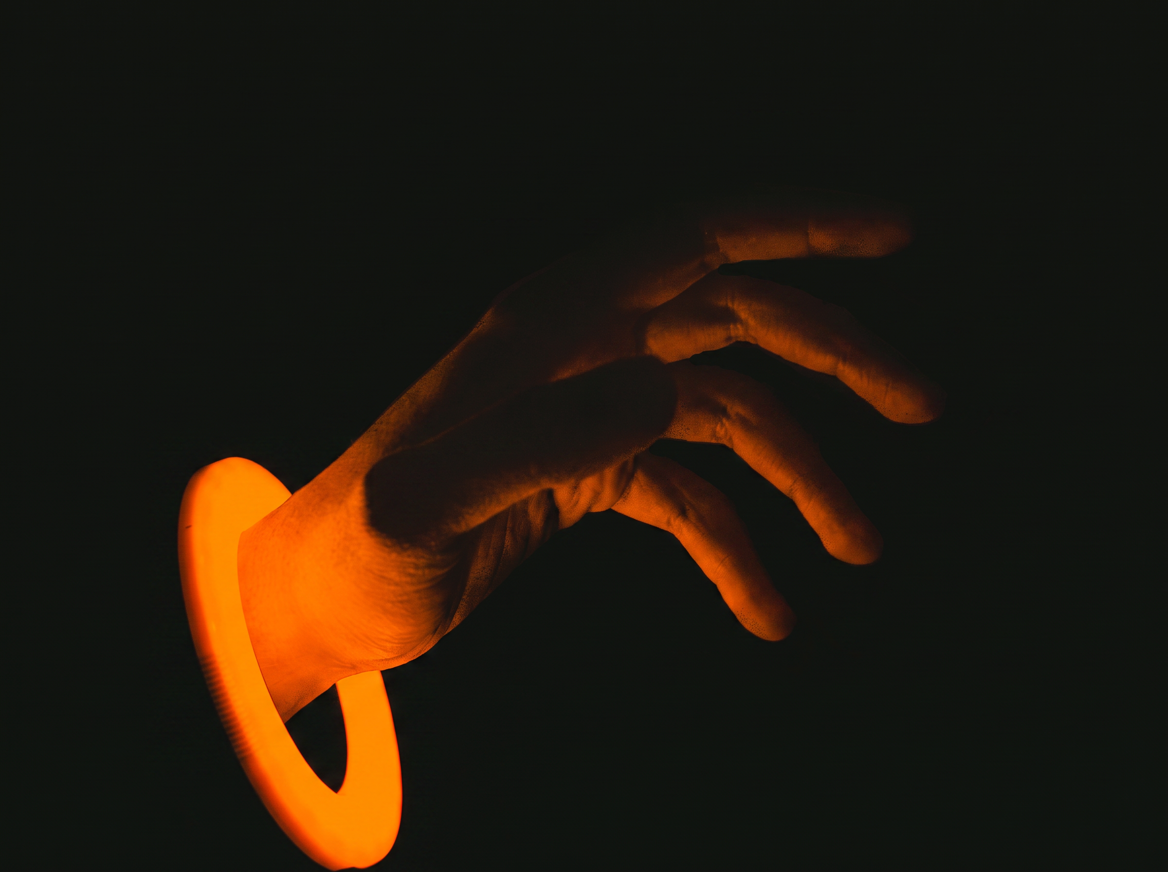 Mano sosteniendo una vela encendida en la oscuridad.