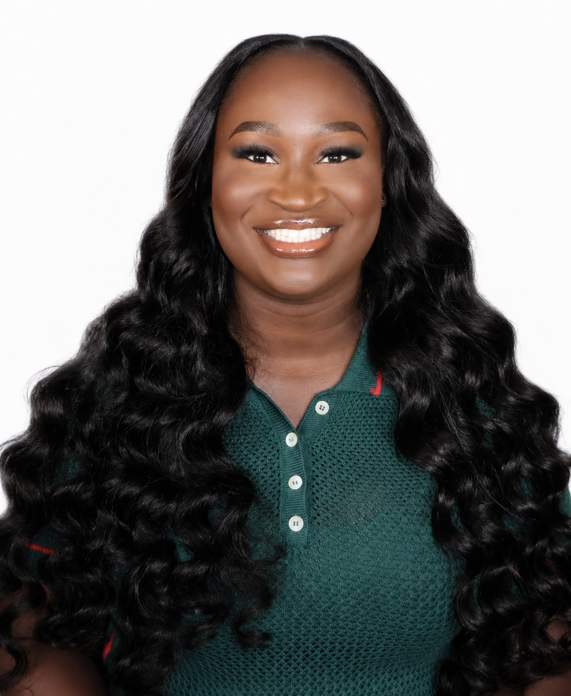 Portrait of a smiling woman with long, wavy black hair, wearing a green collared shirt, against a plain white background.