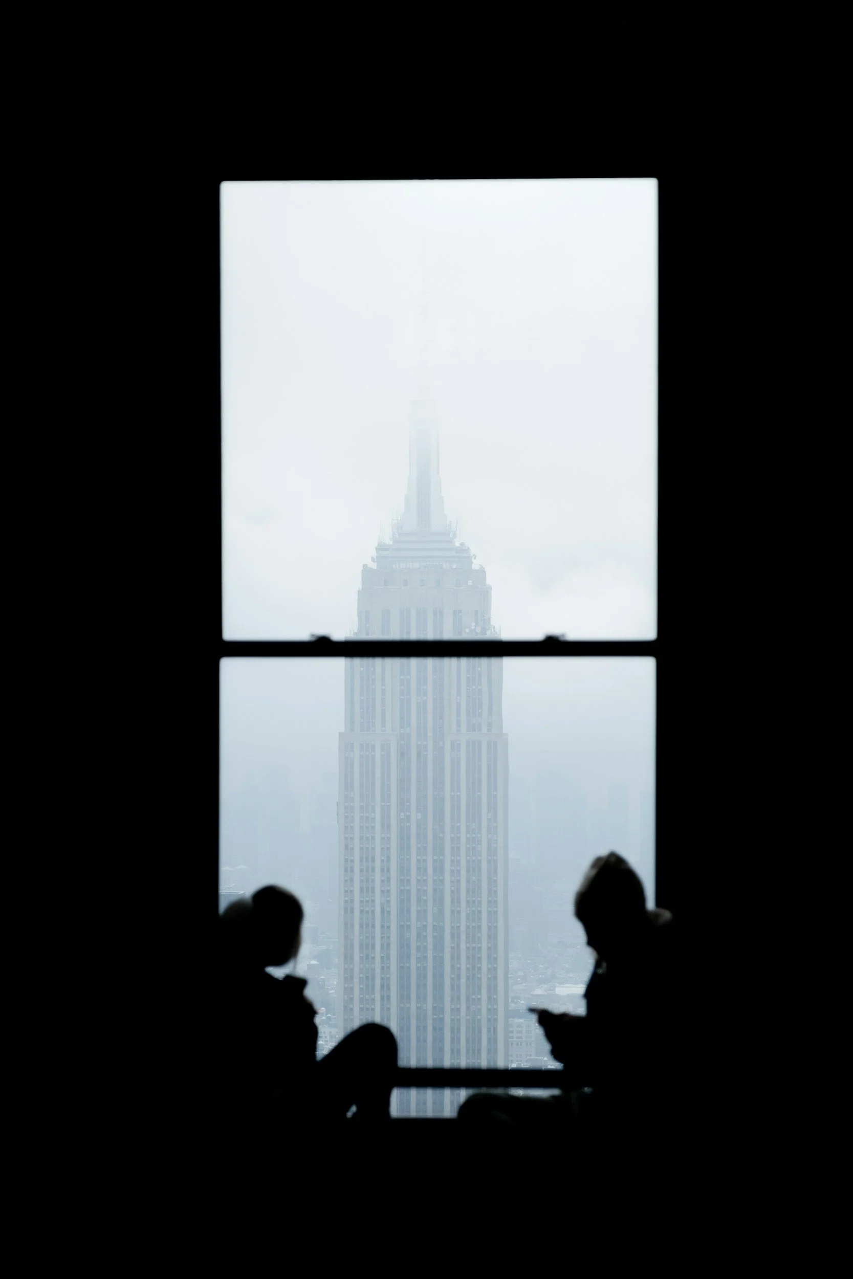 Picture of a a couple sitting at a windowsill overlooking the Empire State Building