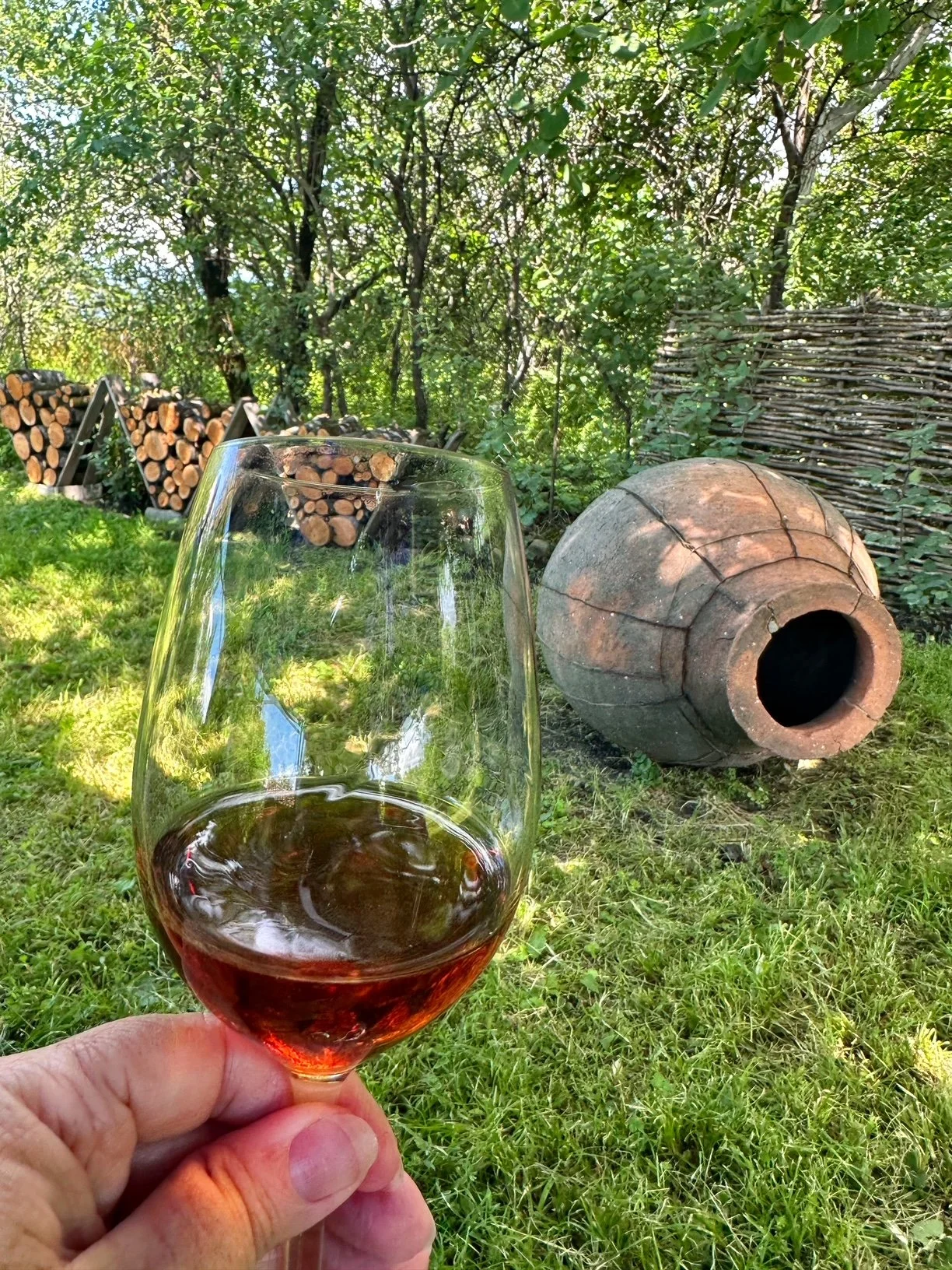 A glass of amber Georgian wine beside a clay qvevri