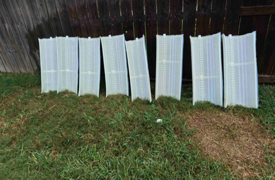 Several hospital or medical respirator masks hanging on a wooden fence to dry outside on the grass.