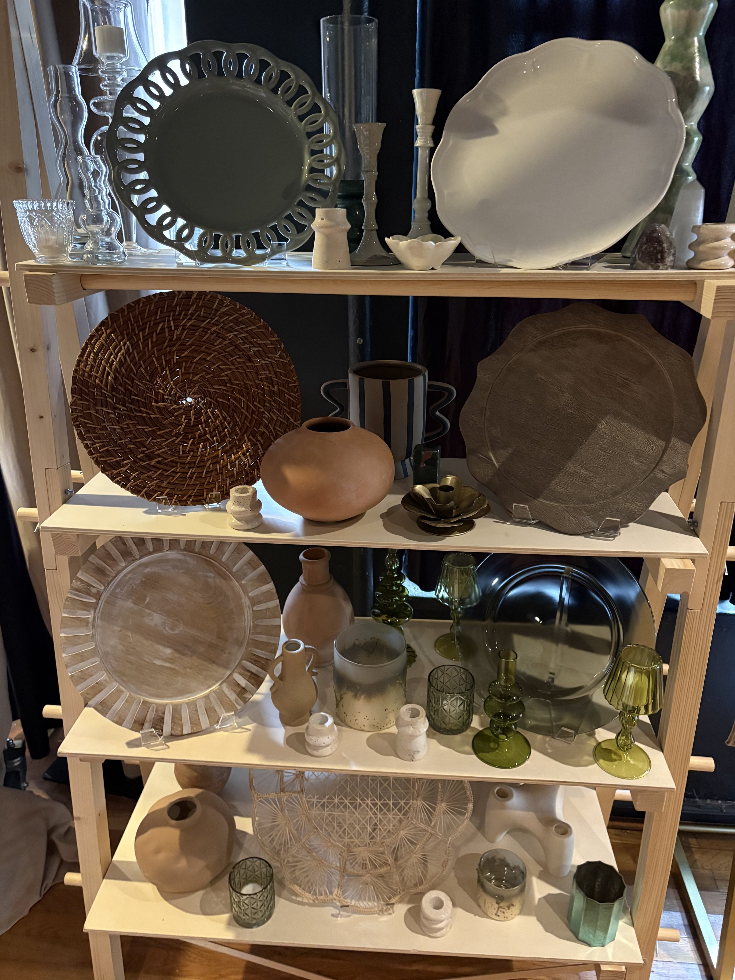 Display shelf with various glass and ceramic decorative objects, including plates, bowls, vases, and candlesticks.
