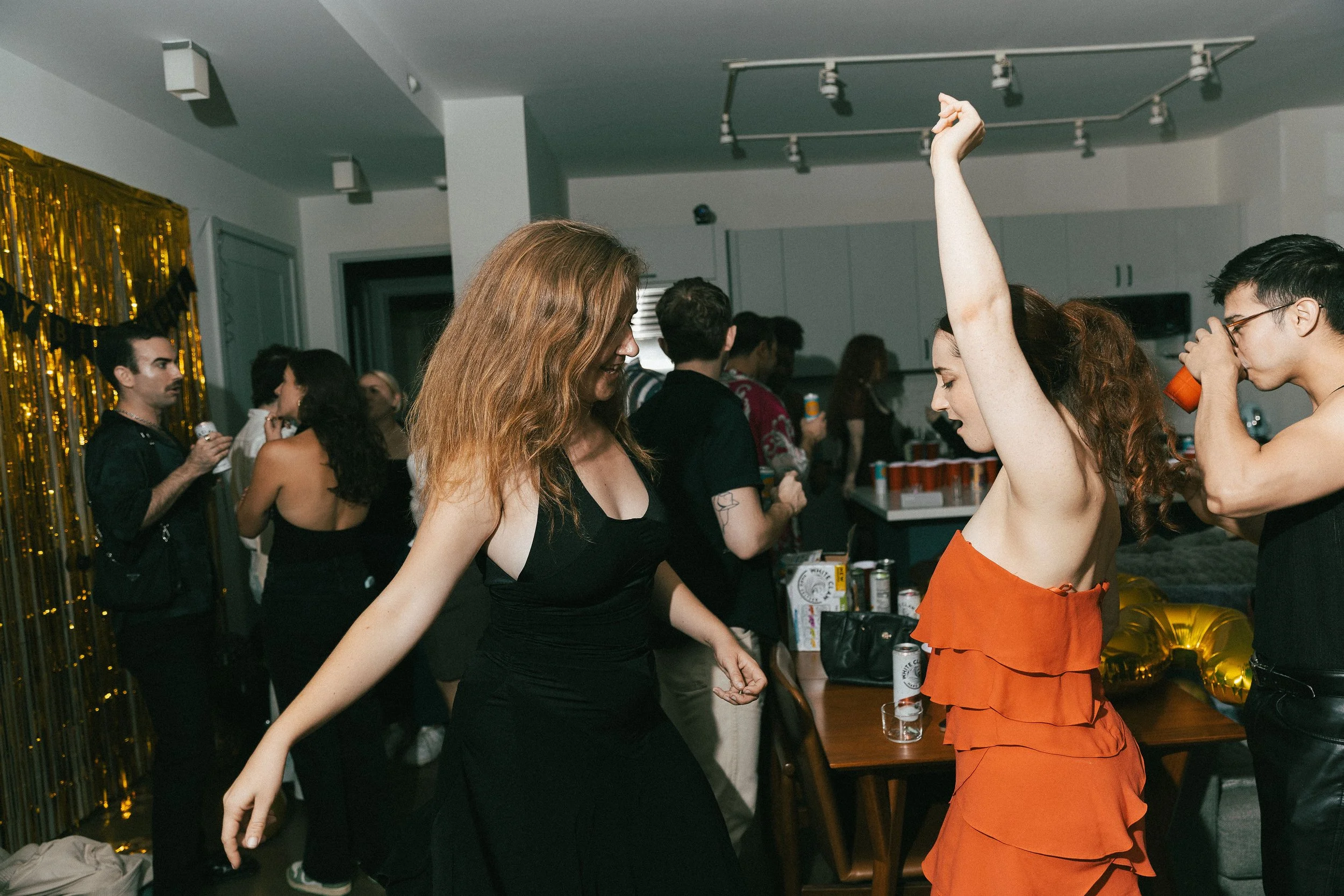People dancing and socializing at a party with decorations and drinks.