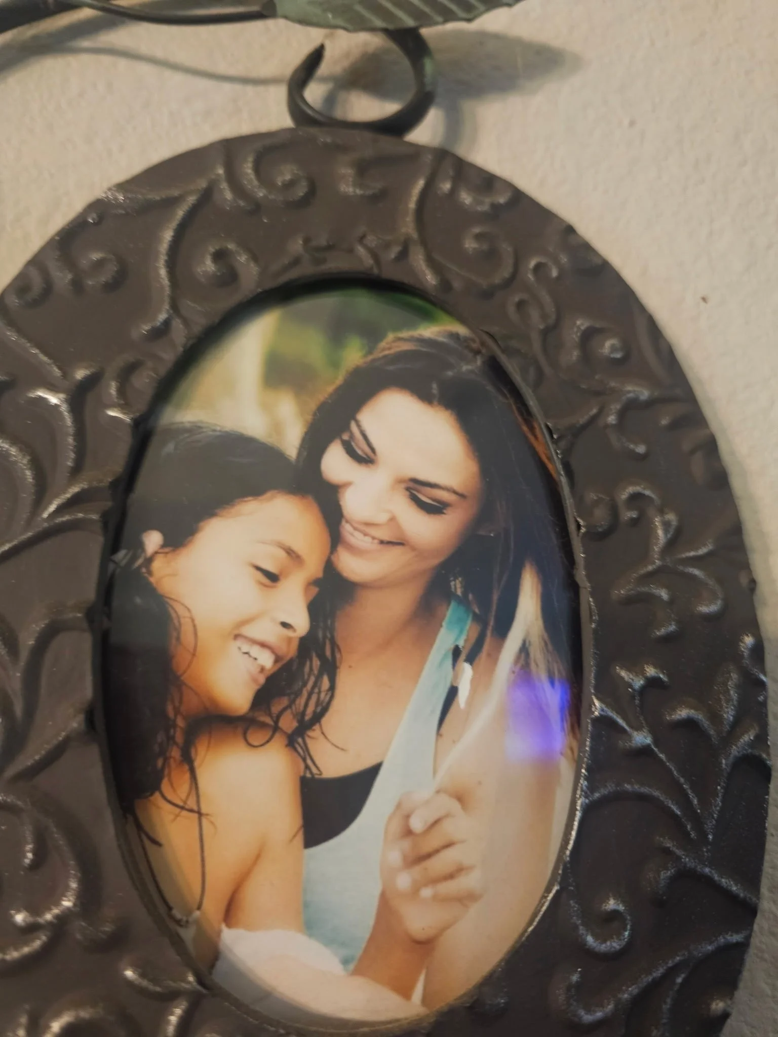 A decorative picture frame with a photo of a woman and a young girl, both smiling and close together.