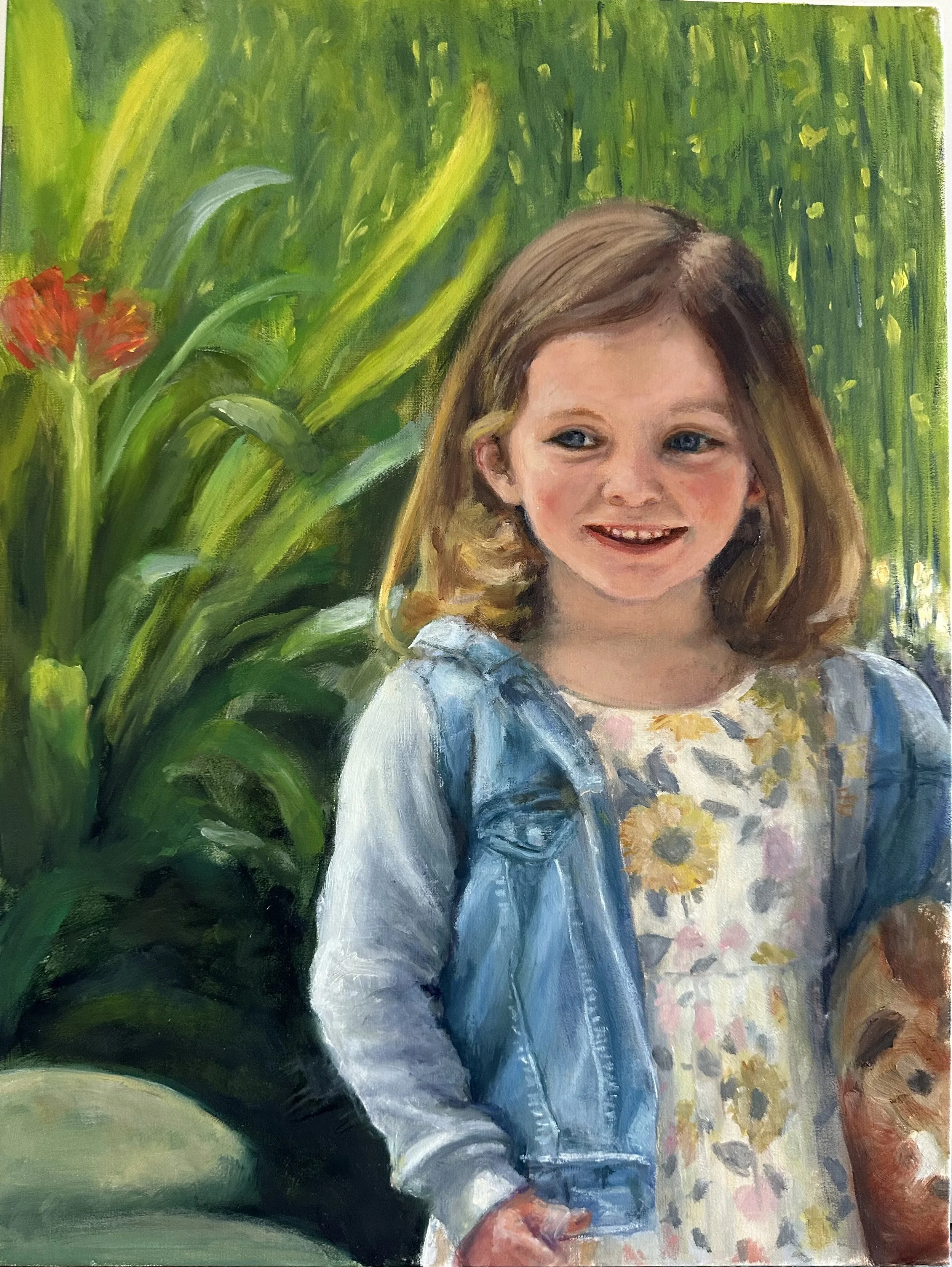 A portrait of a young girl with light brown hair, blue eyes, and a big smile, wearing a floral dress with yellow and white flowers and a denim jacket. The background is a lush green garden with large green leaves and a red flower.