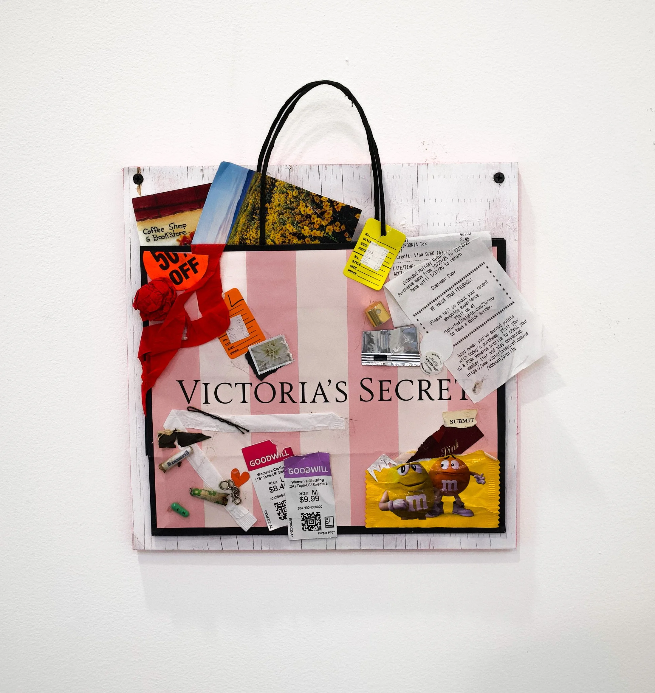 A physical media collage of found objects mounted on white chip board, featuring popular candy wrappers, trash, a Victoria's Secret bag, and Good Will price tags.