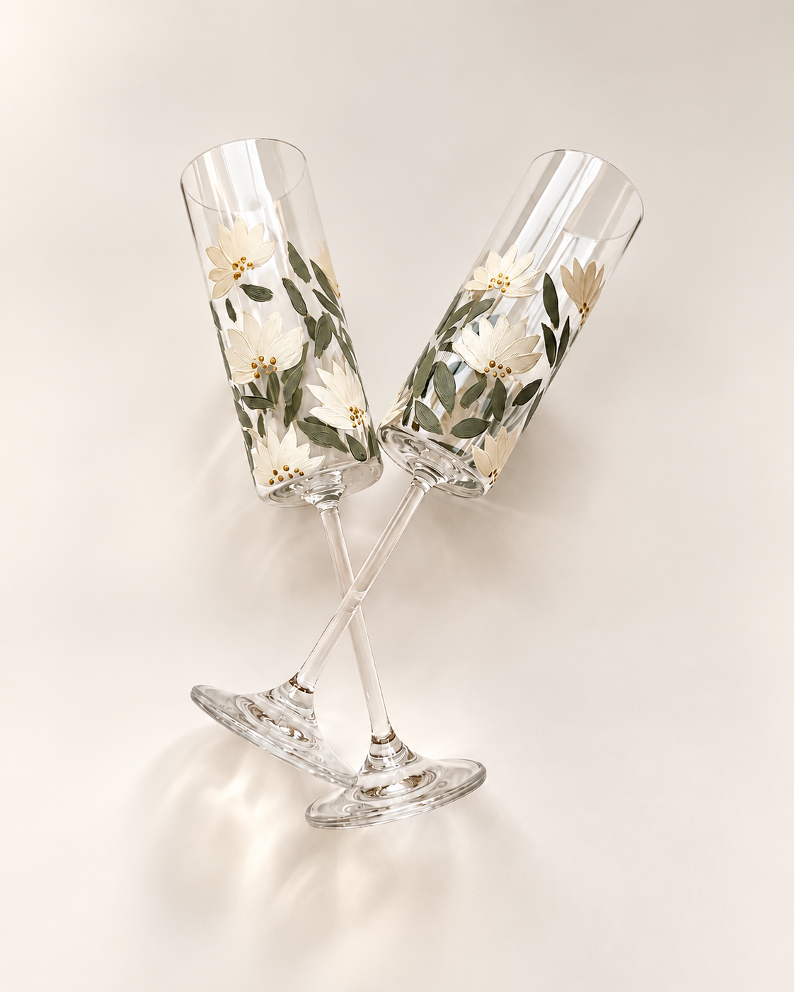 Two champagne flutes with floral pattern design, resting on a light-colored surface.