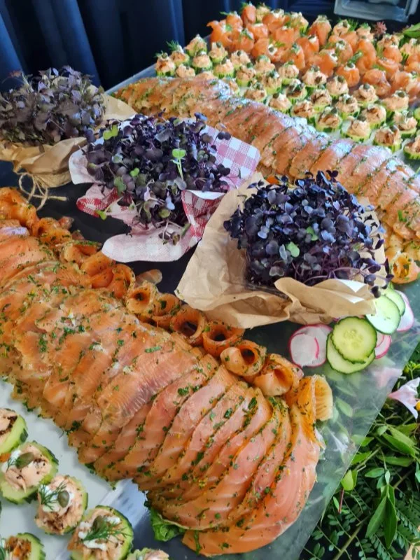 Assorted seafood and appetizer platter with sliced smoked salmon, cucumber and radish slices, and garnishes.