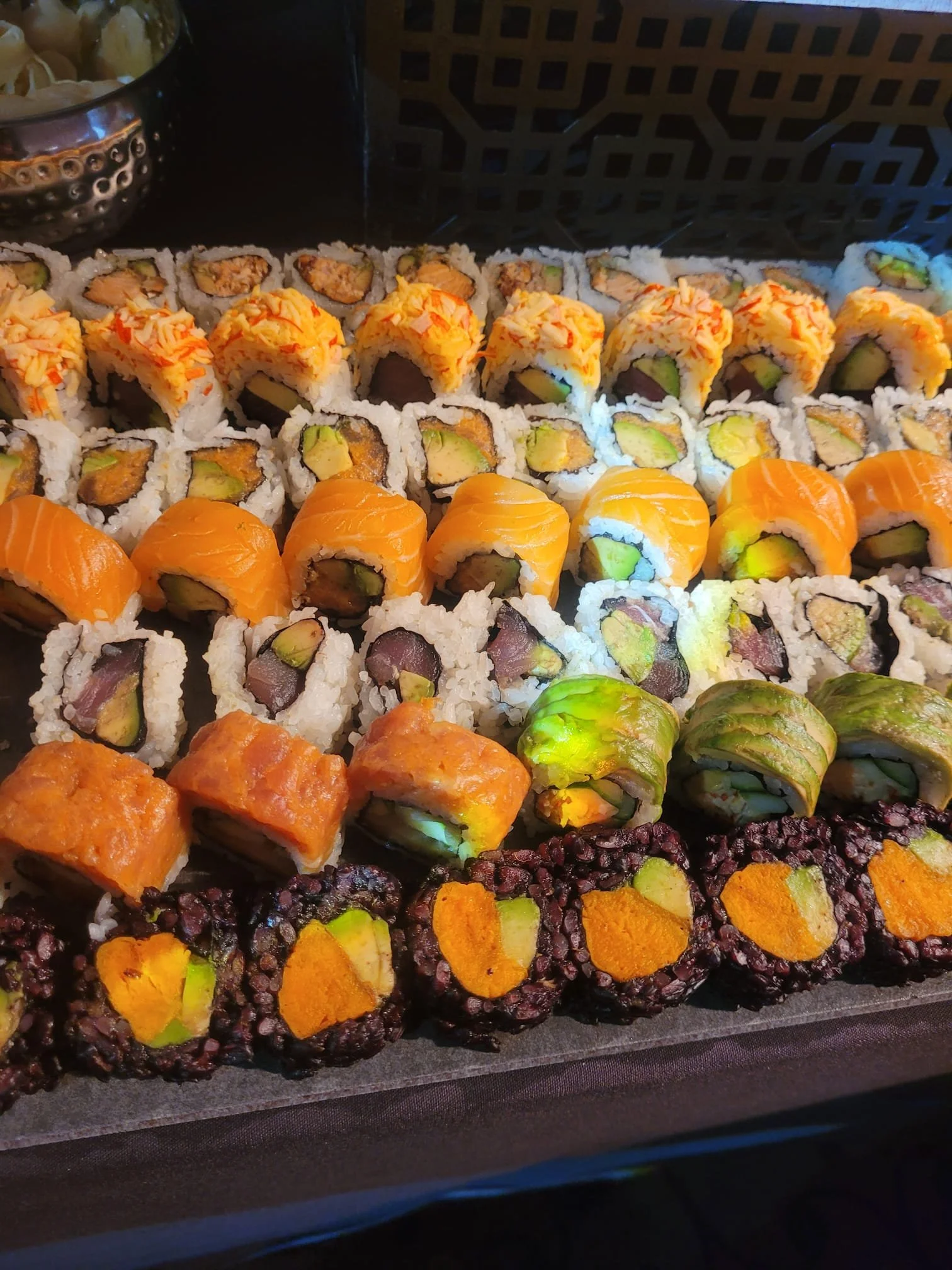 Assorted sushi rolls with various fillings and toppings arranged on a tray.