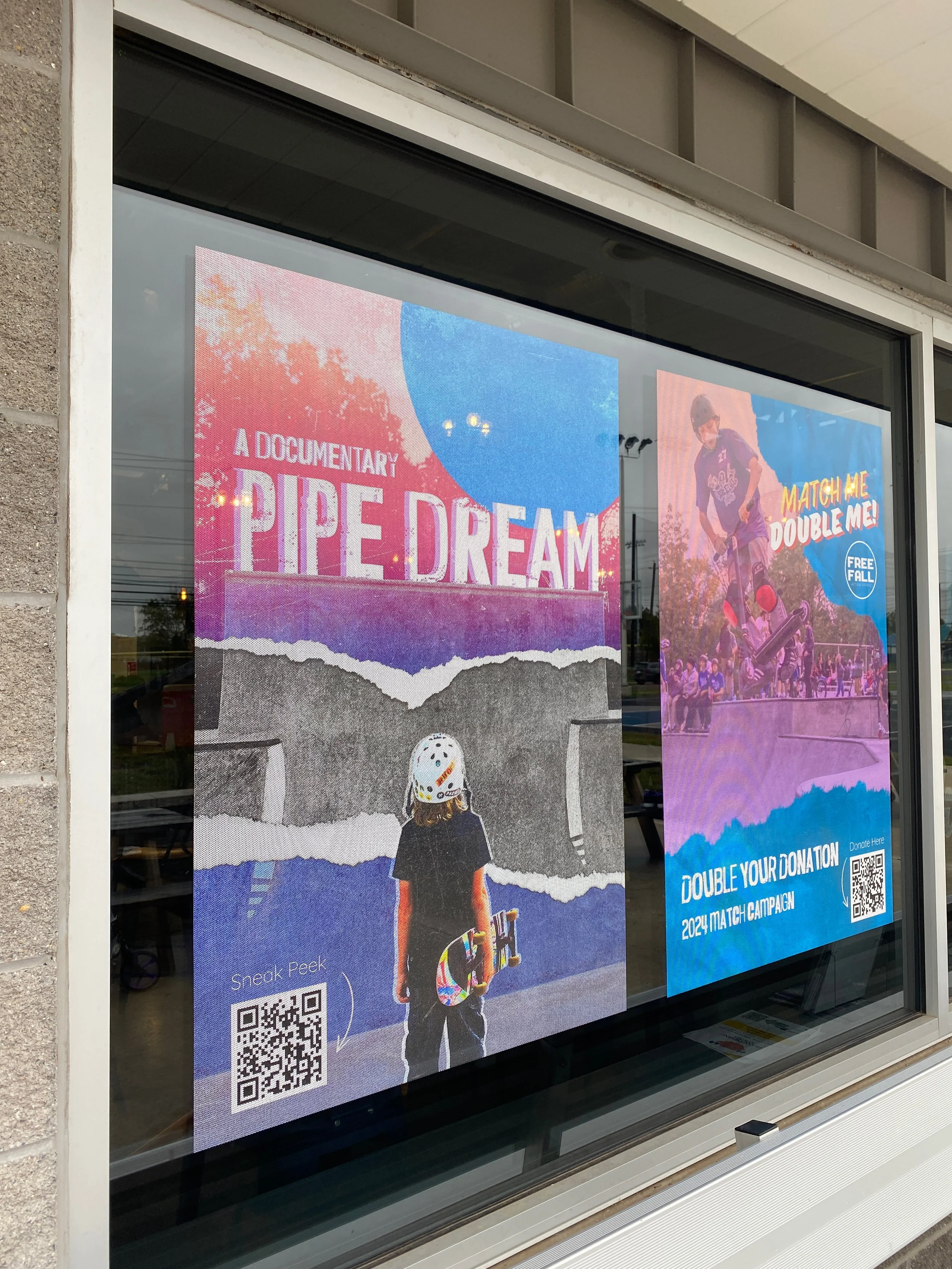 Posters on a glass window advertising a documentary called 'Pipe Dream' and a campaign called 'Match Me Double Me' with a QR code for donation.