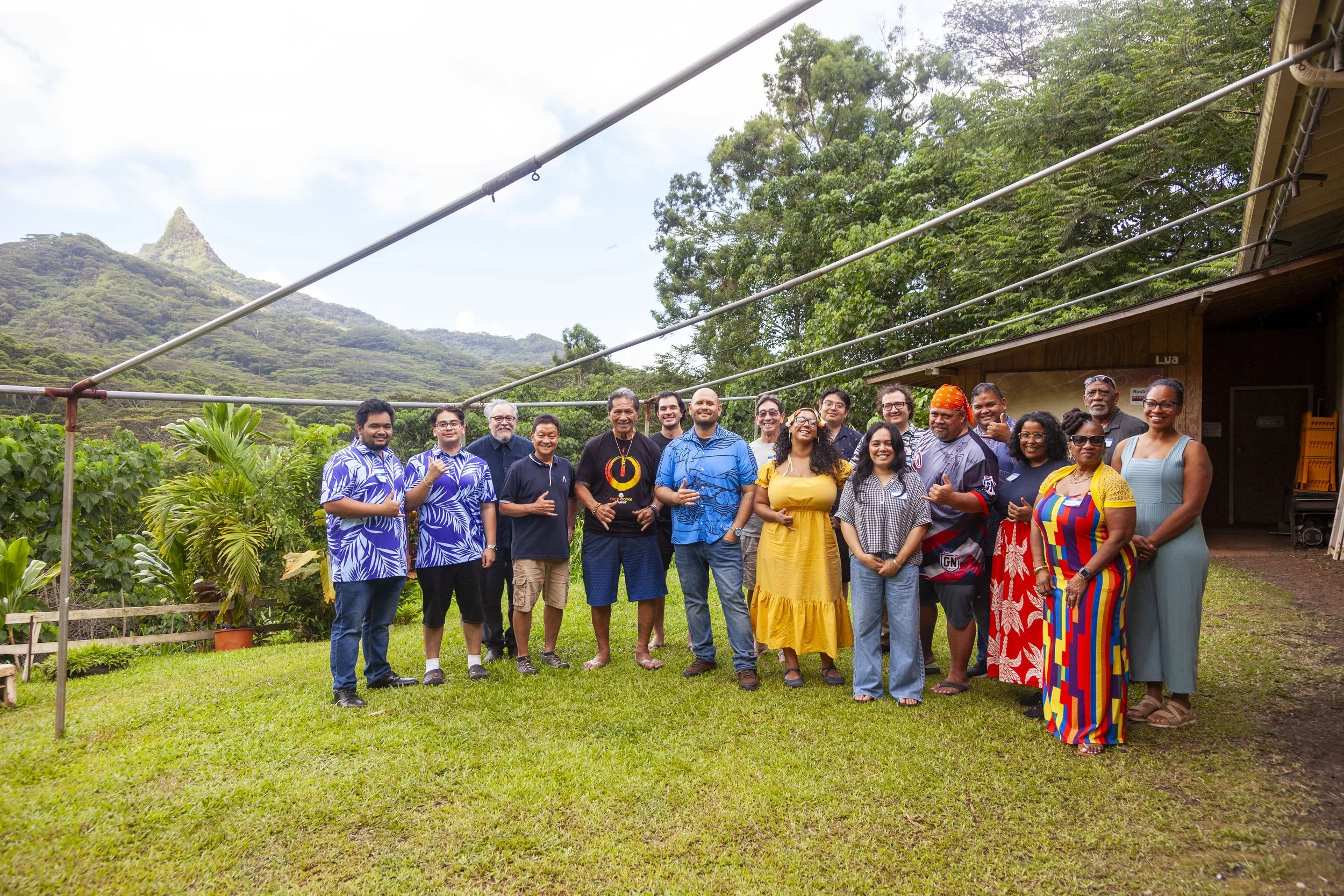 The Nation of Hawai'i. Wiamanulu, HI. A group of diverse people standing outdoors in a lush green garden with hills in the background, smiling for a group photo.