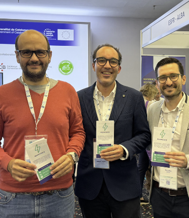 Three men standing indoors at a professional event, smiling and holding conference badges.