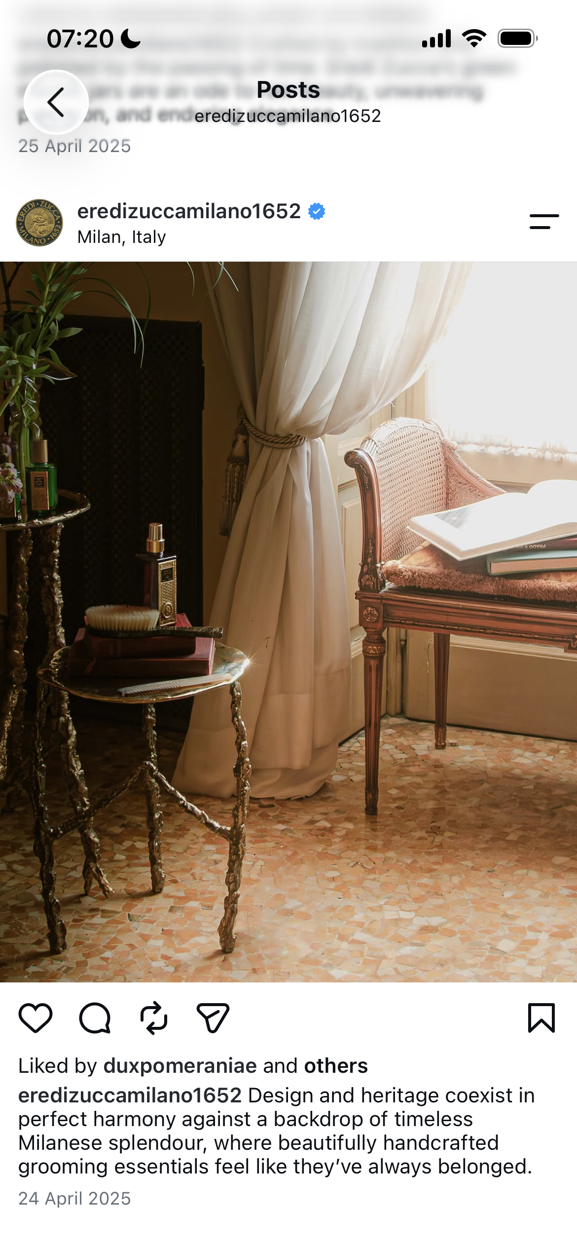 A vintage-style room with a wooden settee, white curtains, a small ornate table with grooming items, and sunlight streaming through the window.