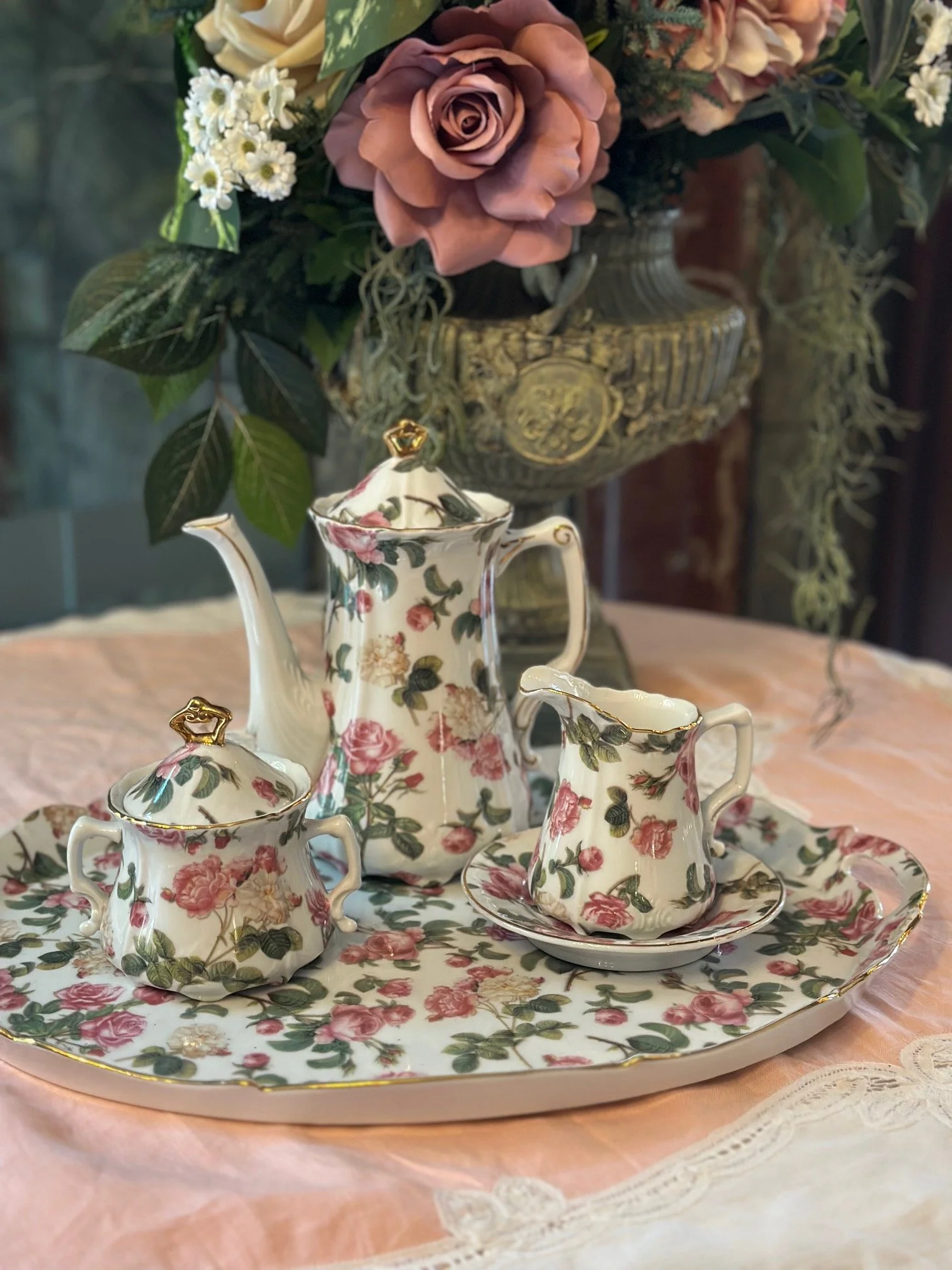 Floral porcelain tea set surrounded by fresh flowers and roses.