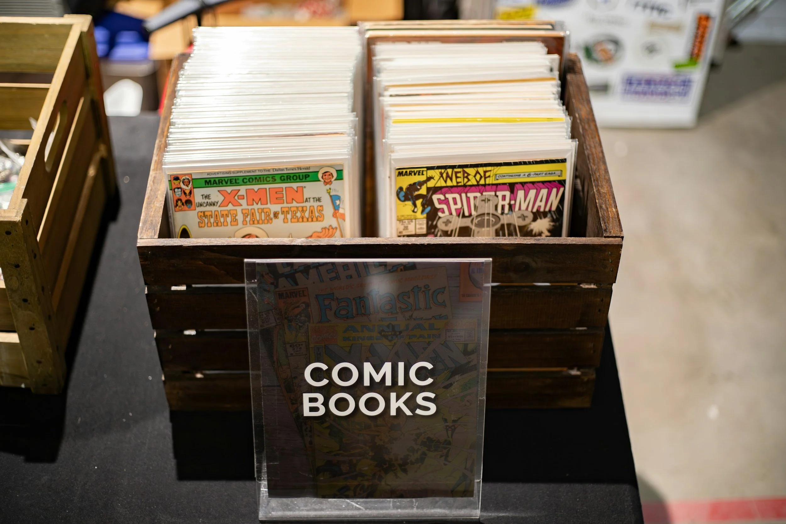 A display of comic books in a wooden bin at a store.