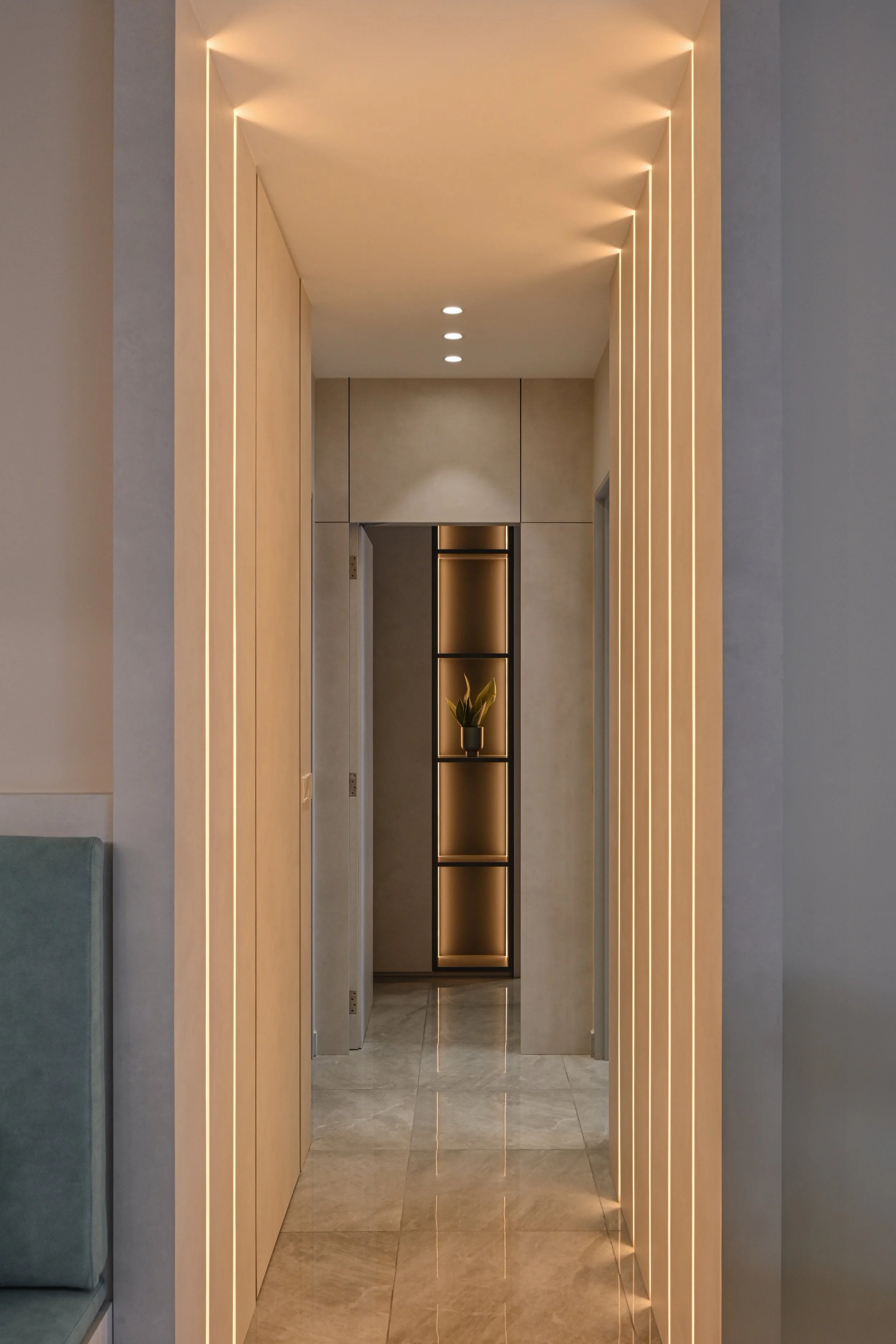 Modern interior hallway with warm lighting, light-colored walls, and a decorative bookshelf with a potted plant at the end.