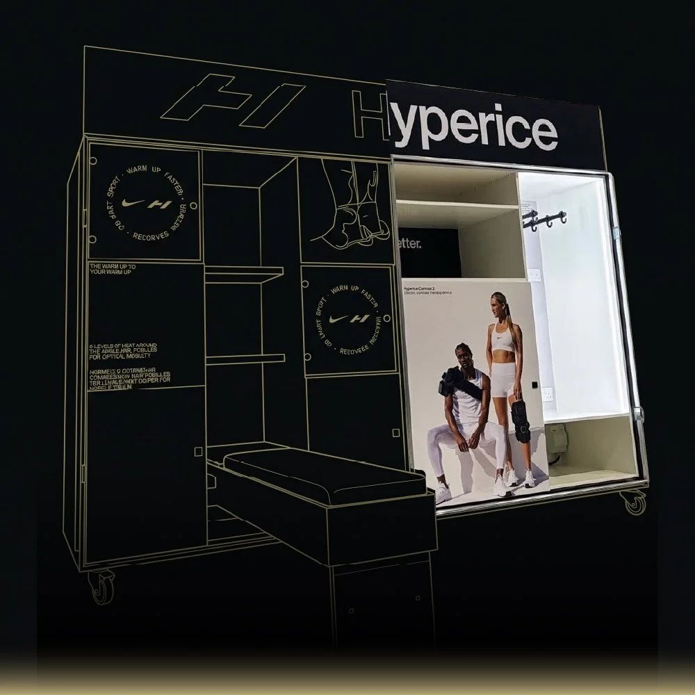 A display booth for Nike Hyperice with a black background, white outline illustrations, and a large poster of two athletes in Nike sportswear.