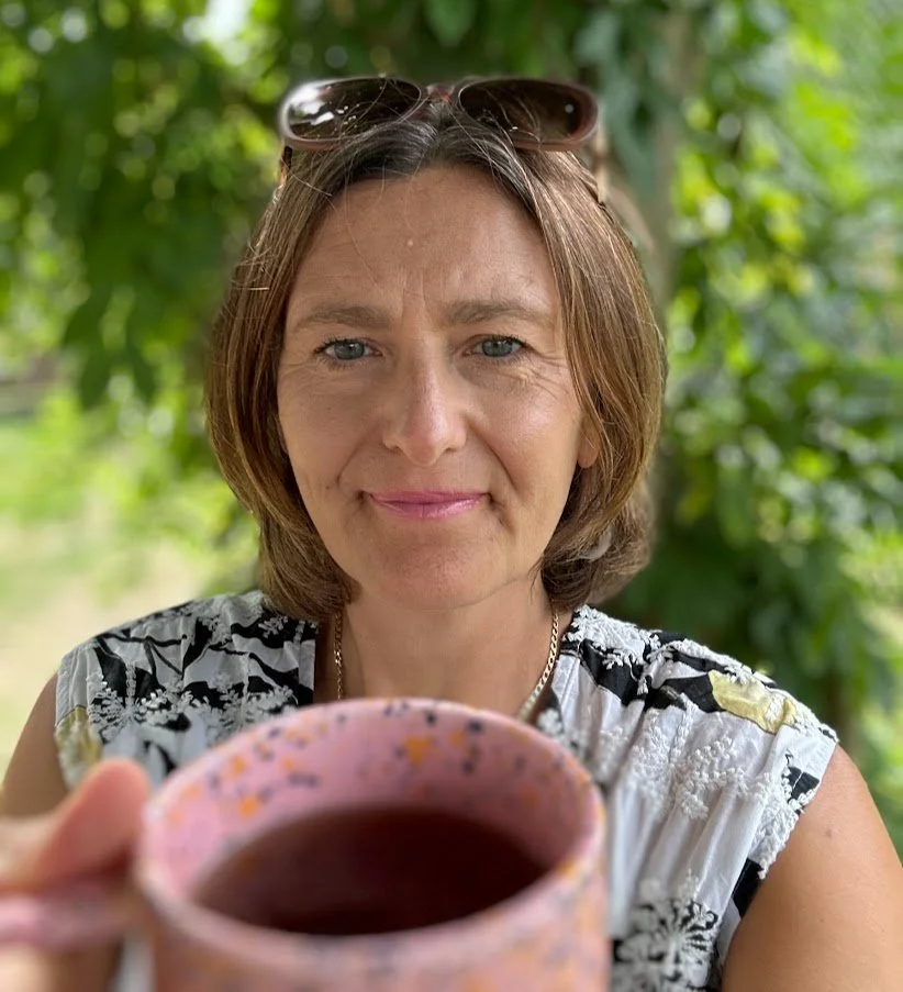 A woman raises a cup of tea in toast to overcoming overwhelm.