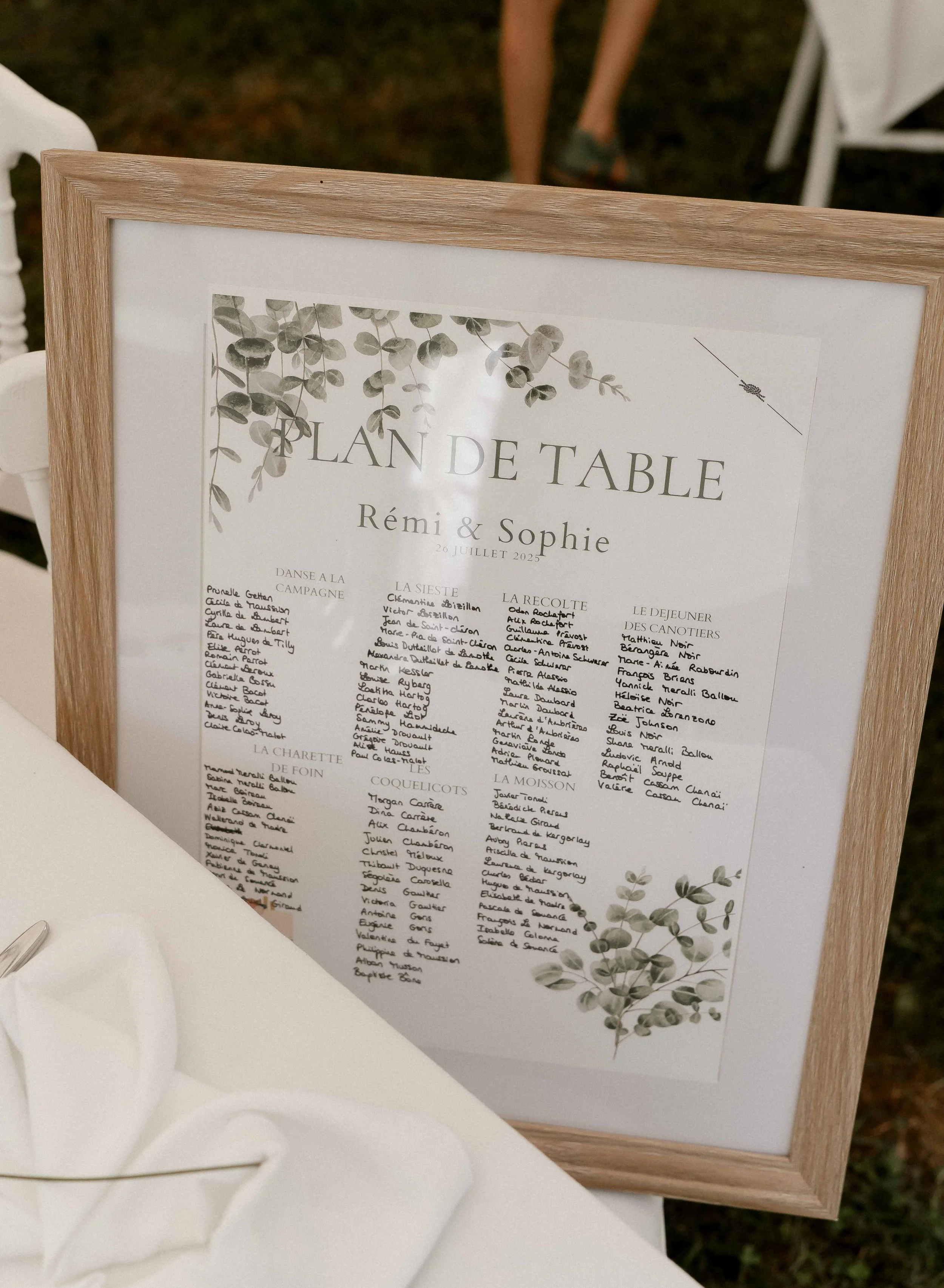 Carte de l'événement mariage avec inscription 'Plan de table' et noms des mariés Rémi & Sophie, datée du 26 juillet 2025, décoration florale en haut à gauche et en bas à droite.